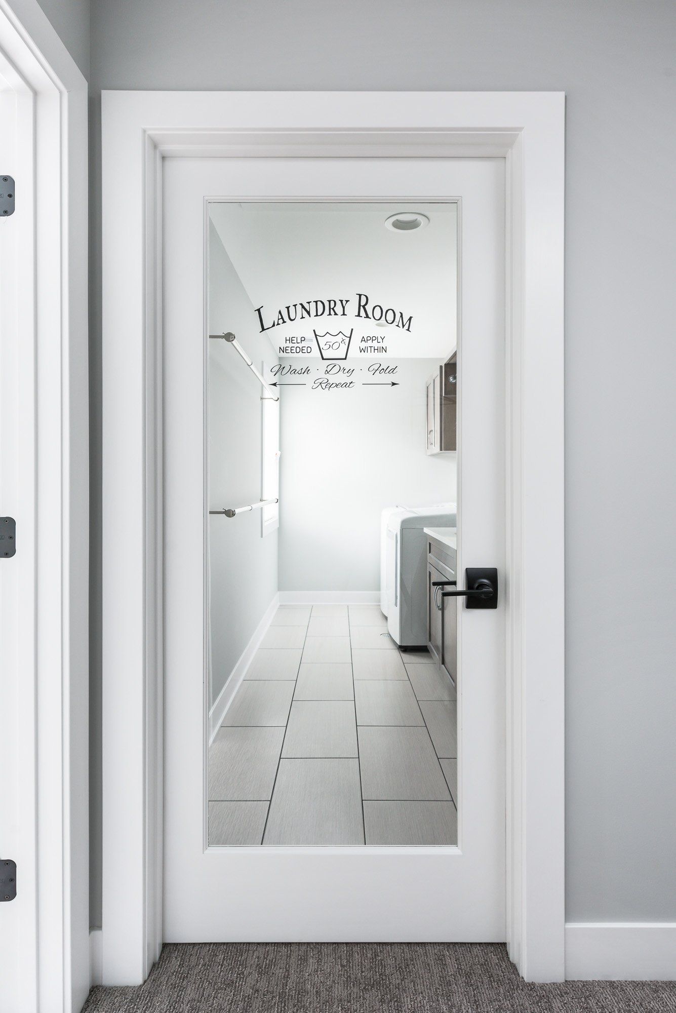 A laundry room with a glass door and a tiled floor.