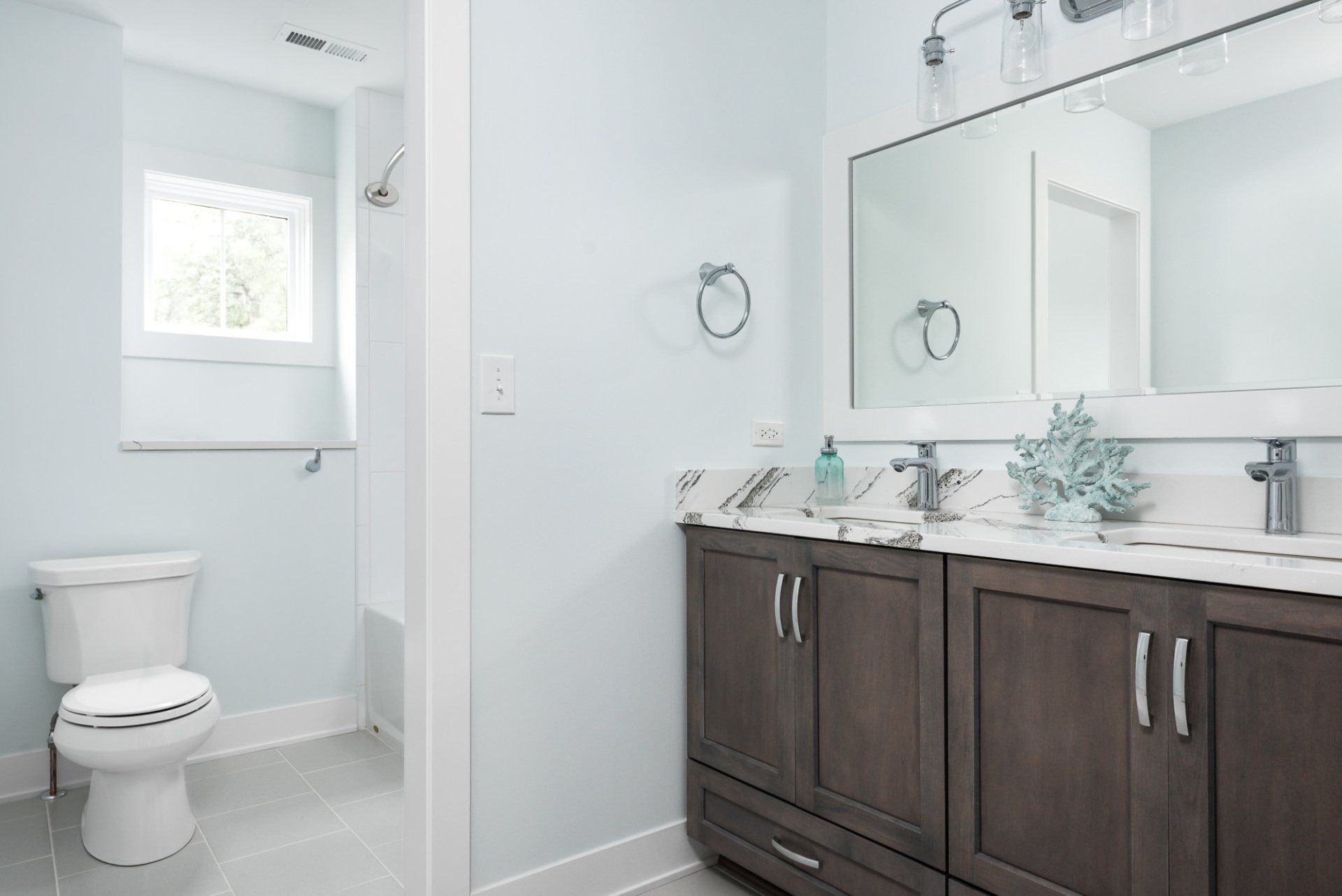 A bathroom with a toilet , sink , mirror and shower.