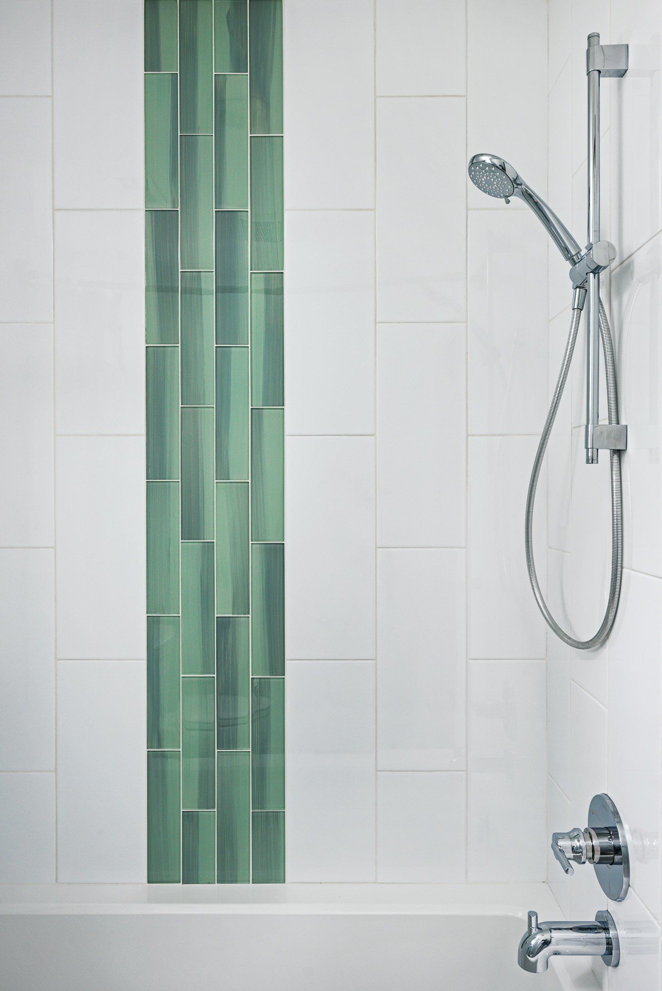 A shower with green tiles on the wall and a bathtub