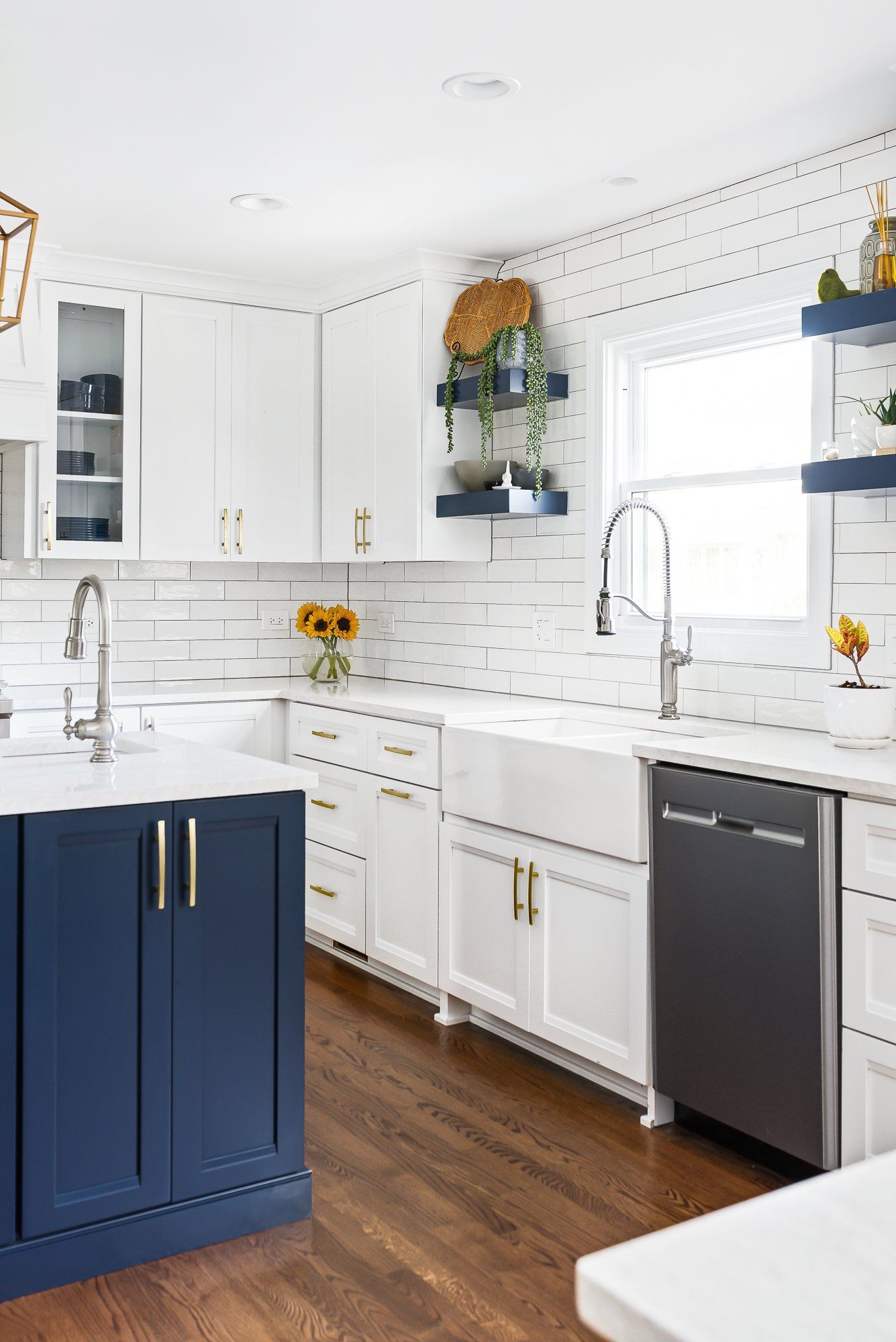 A kitchen with blue cabinets , white cabinets , a sink , and a dishwasher.