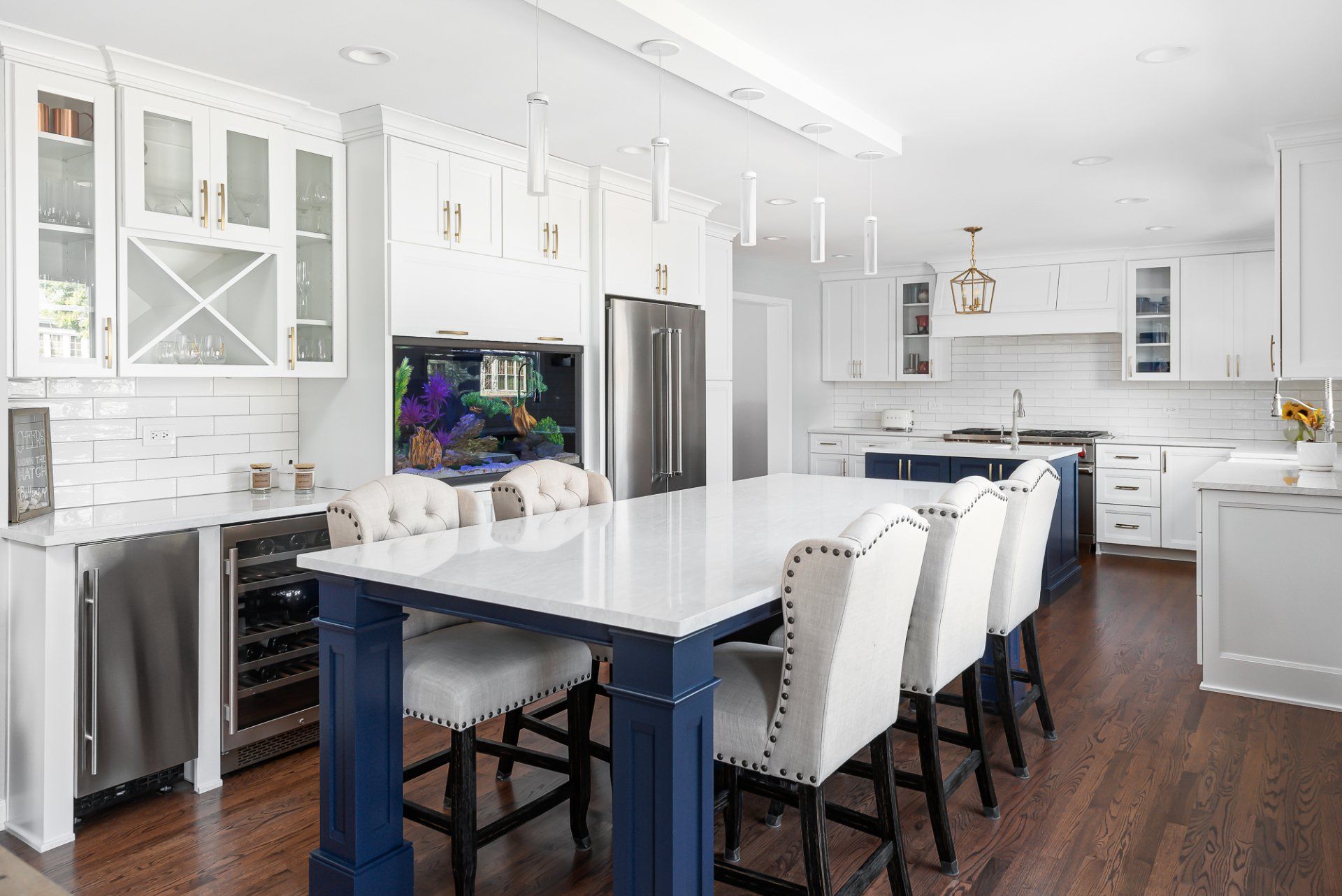 A kitchen with white cabinets and a blue island with a dining table and chairs.