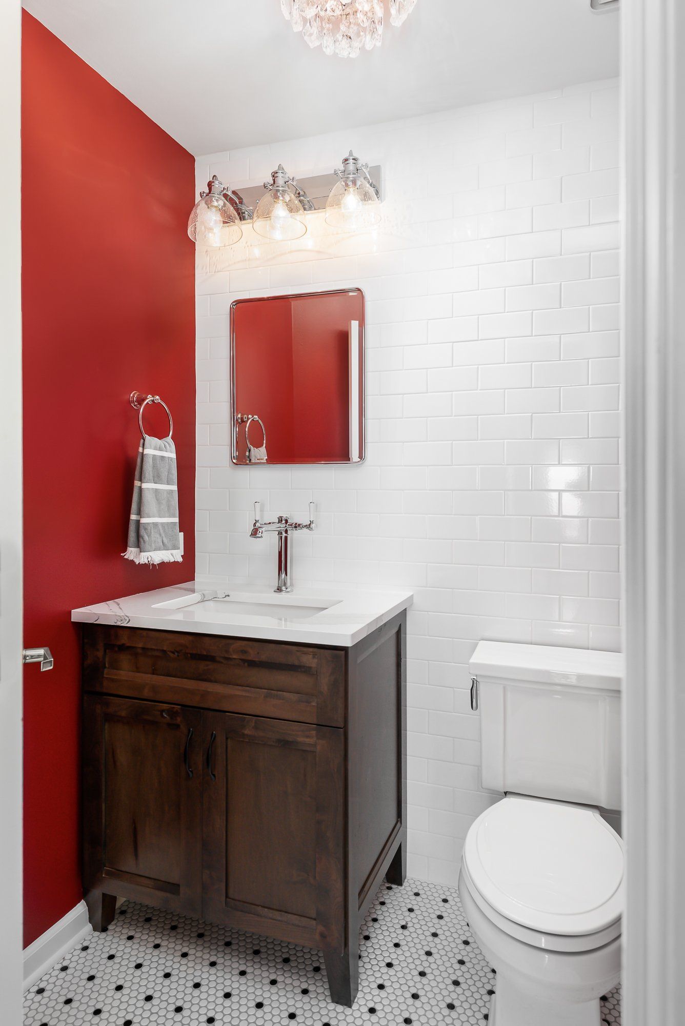 A bathroom with a sink , toilet , mirror and red walls.