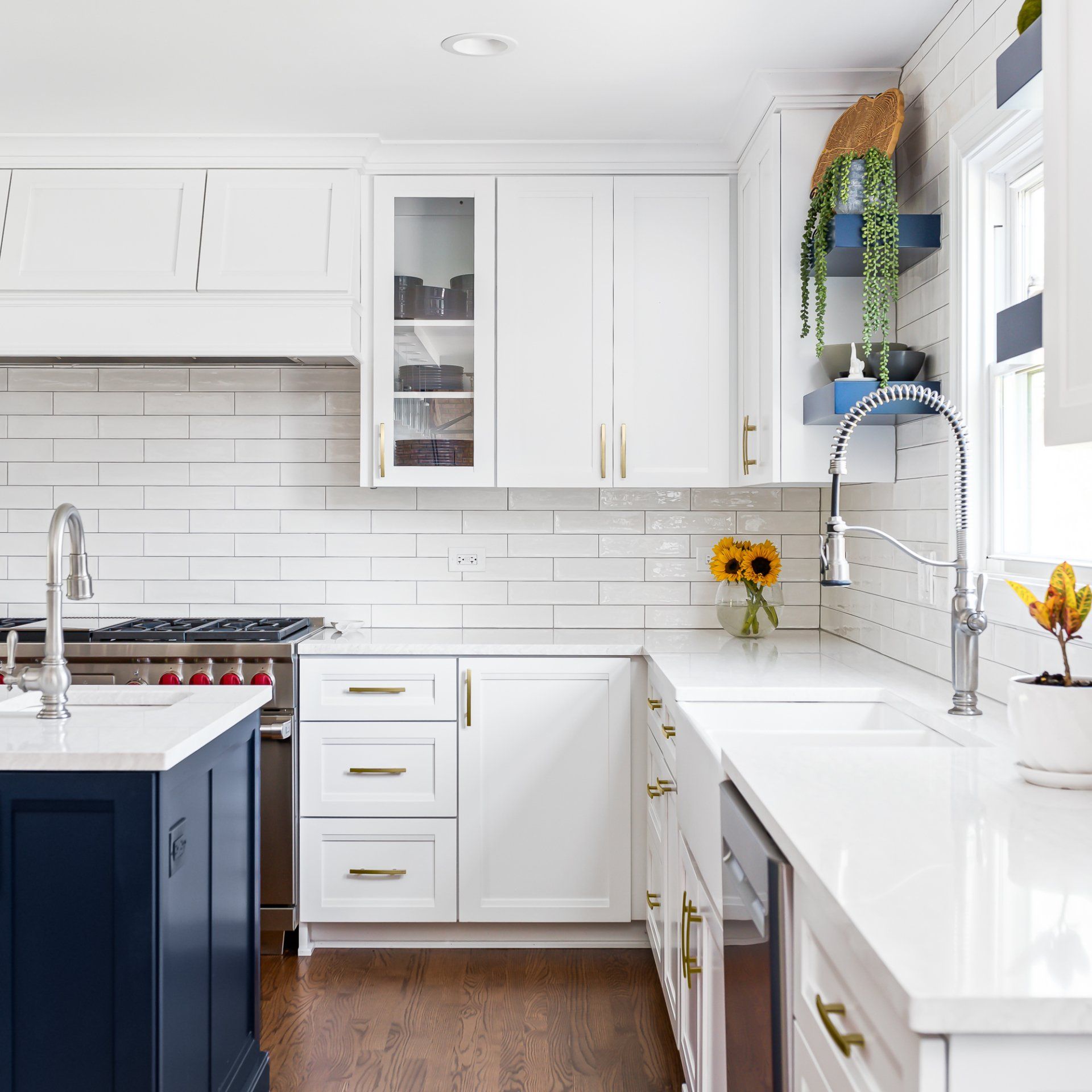 A kitchen with white cabinets , a sink , a stove and a window.
