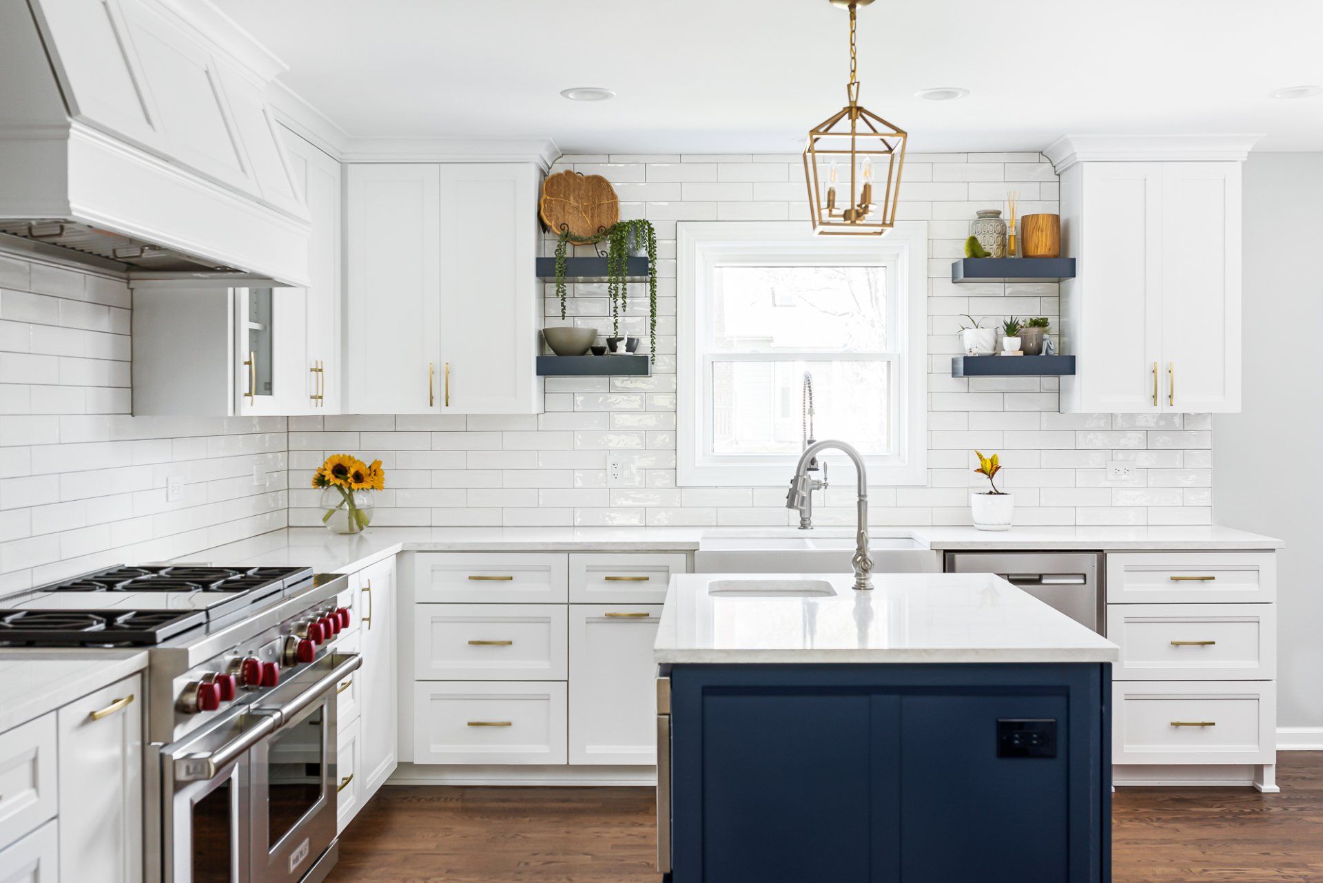 A kitchen with white cabinets , stainless steel appliances , and a blue island.