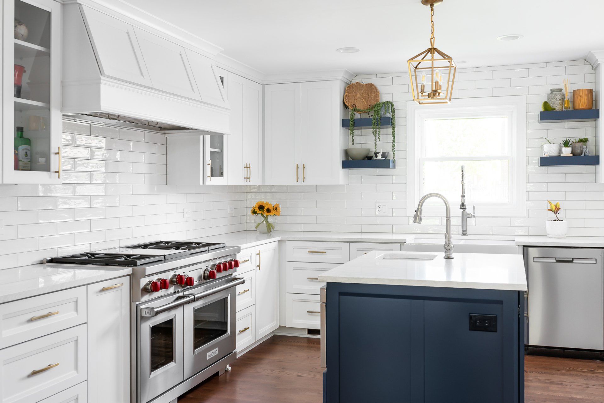 A kitchen with white cabinets , stainless steel appliances , and a blue island.