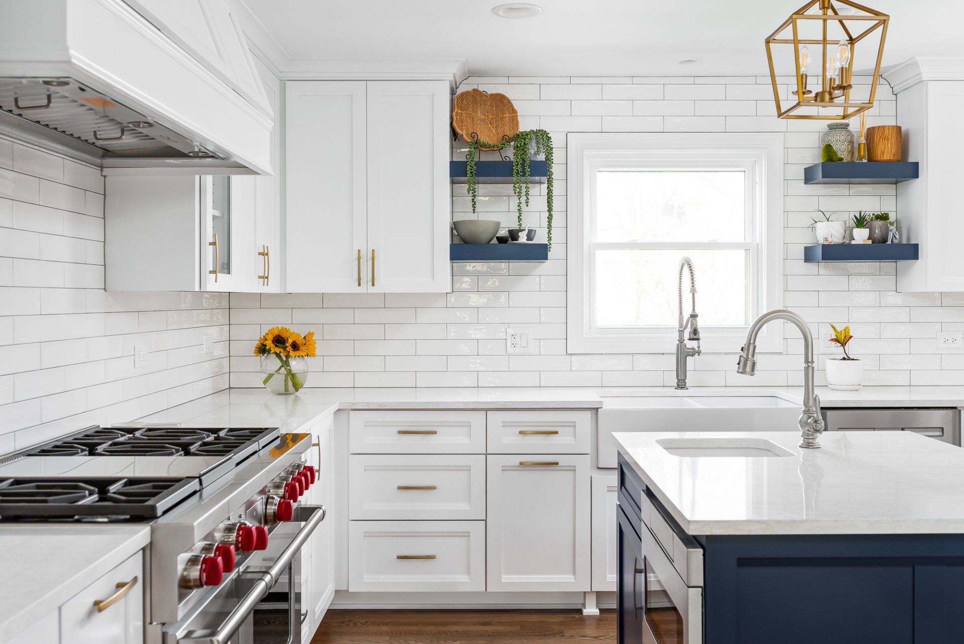 A kitchen with white cabinets , a stove , a sink , and a window.