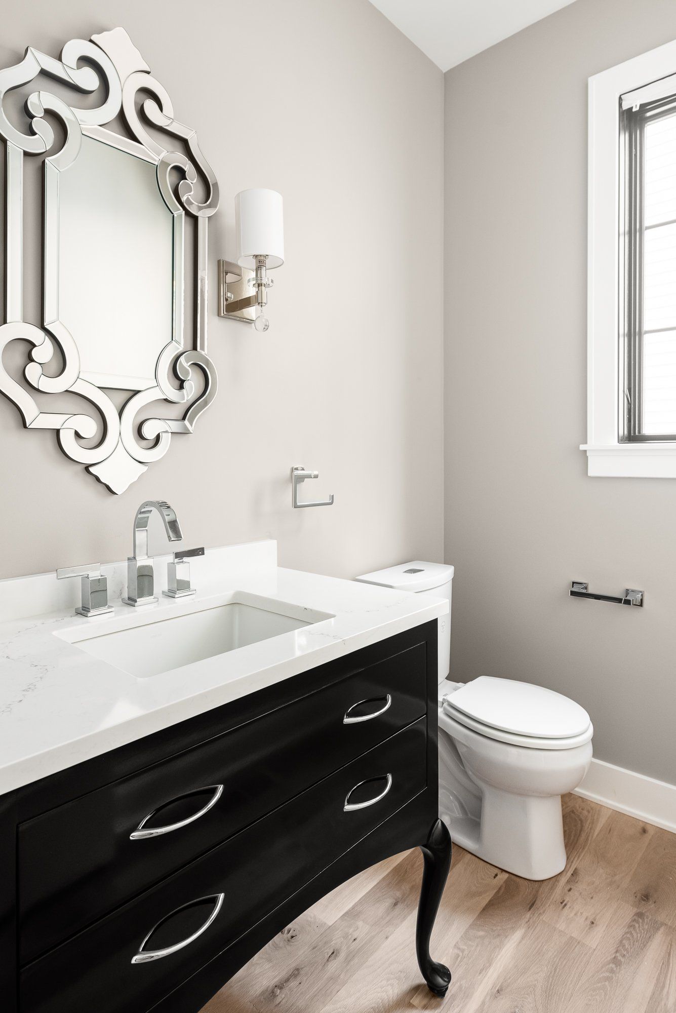 A bathroom with a sink , toilet , mirror and window.