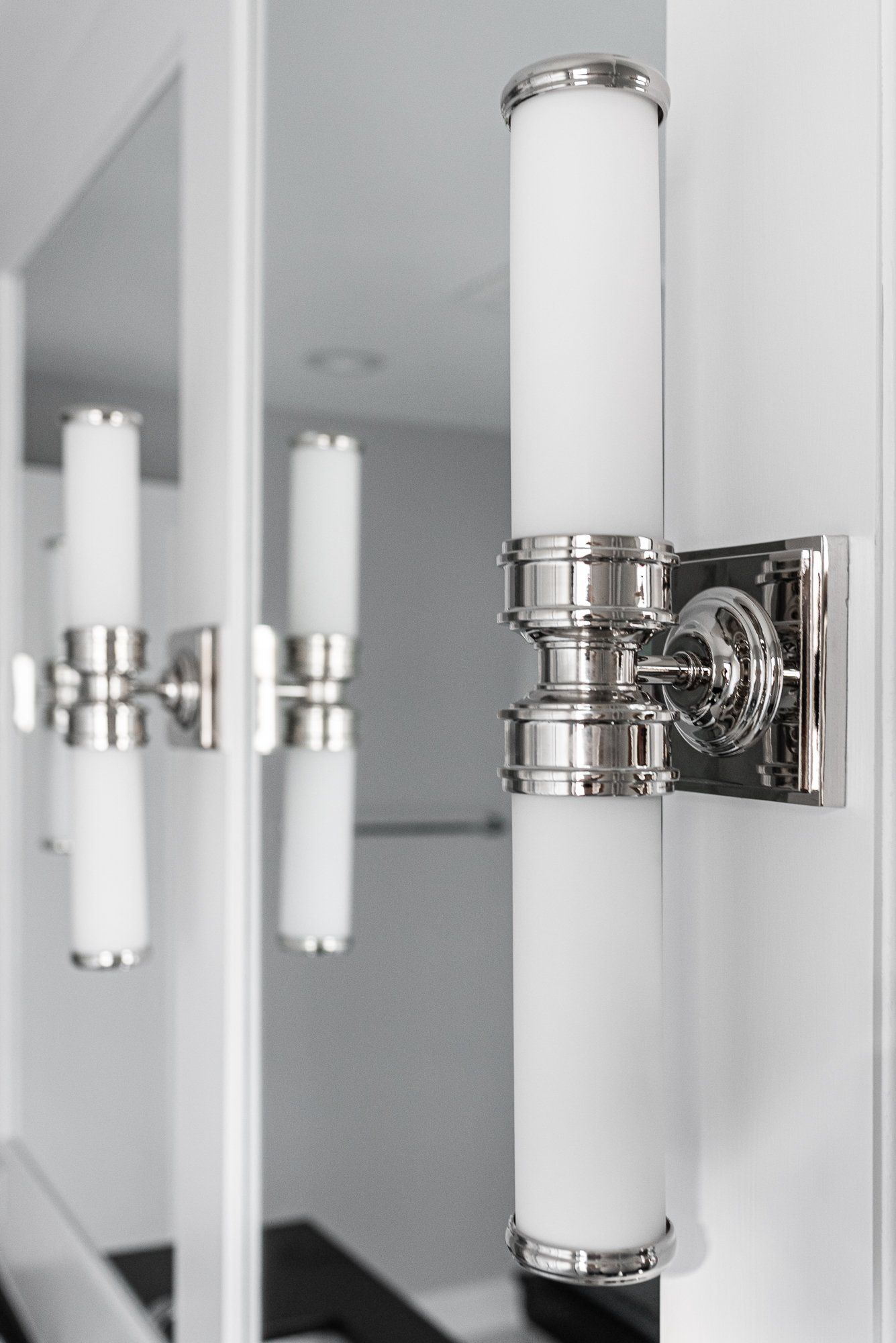 A bathroom with a mirror and a light on the wall.