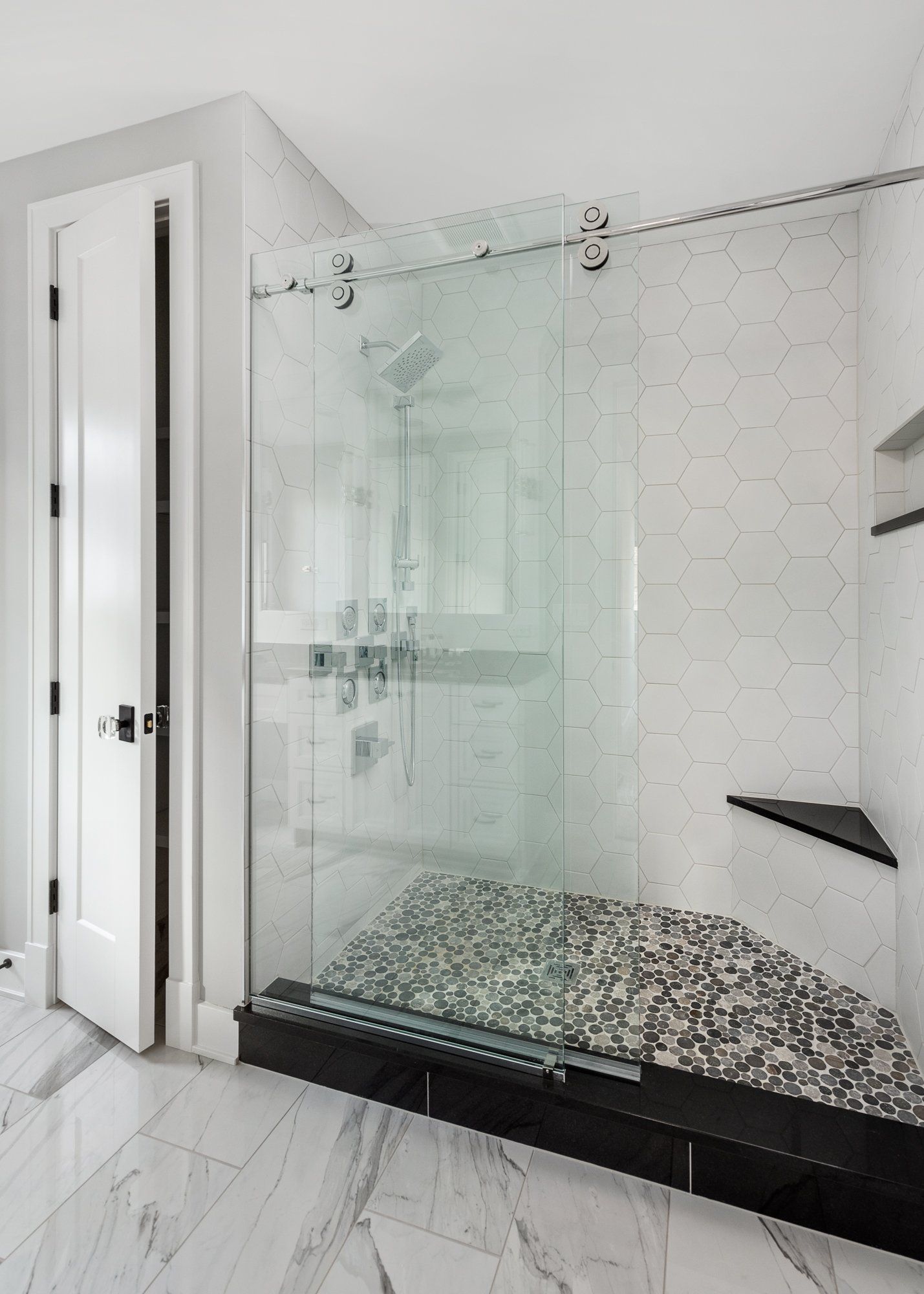 A bathroom with a walk in shower with a glass door.