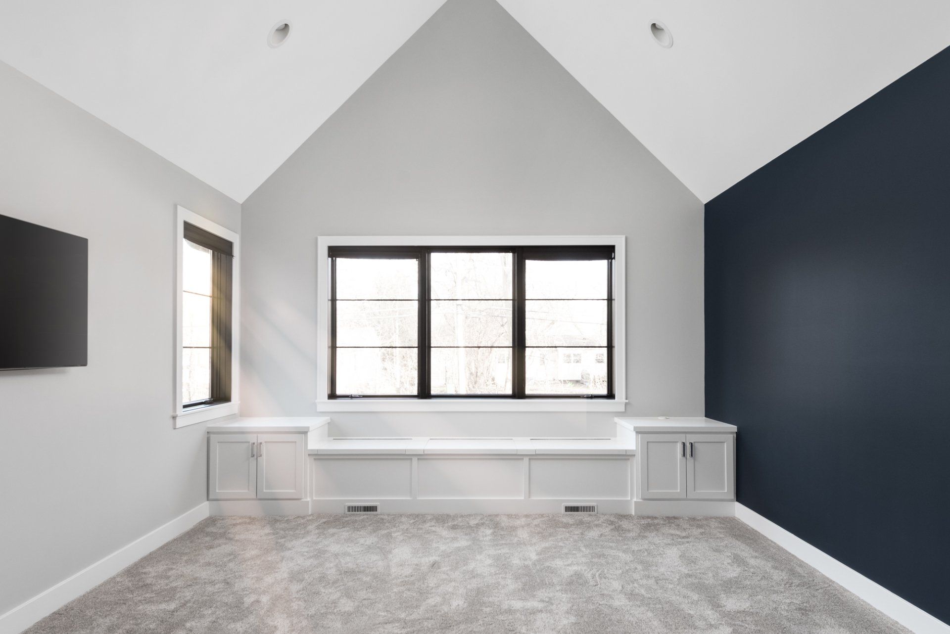 An empty room with a vaulted ceiling and a large window.