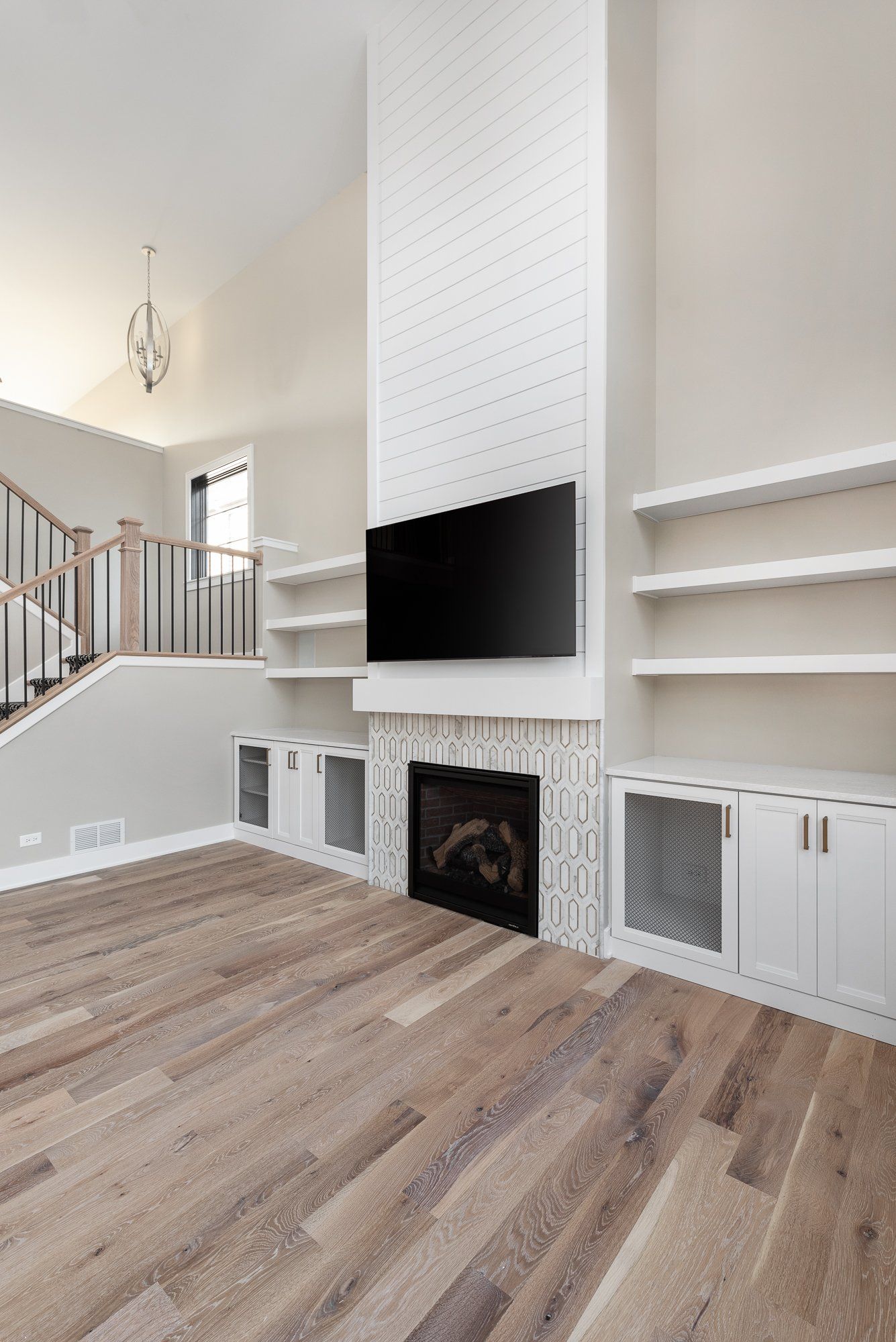 A living room with hardwood floors , a fireplace and a flat screen tv.