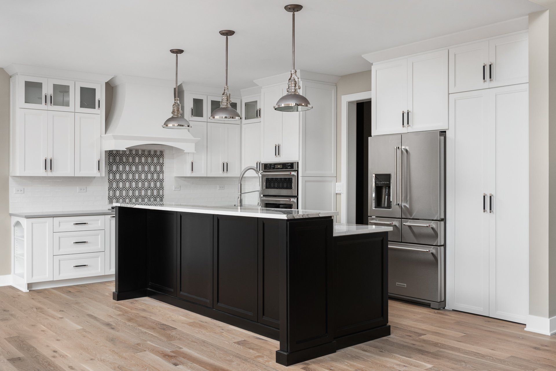 A kitchen with white cabinets and a black island.
