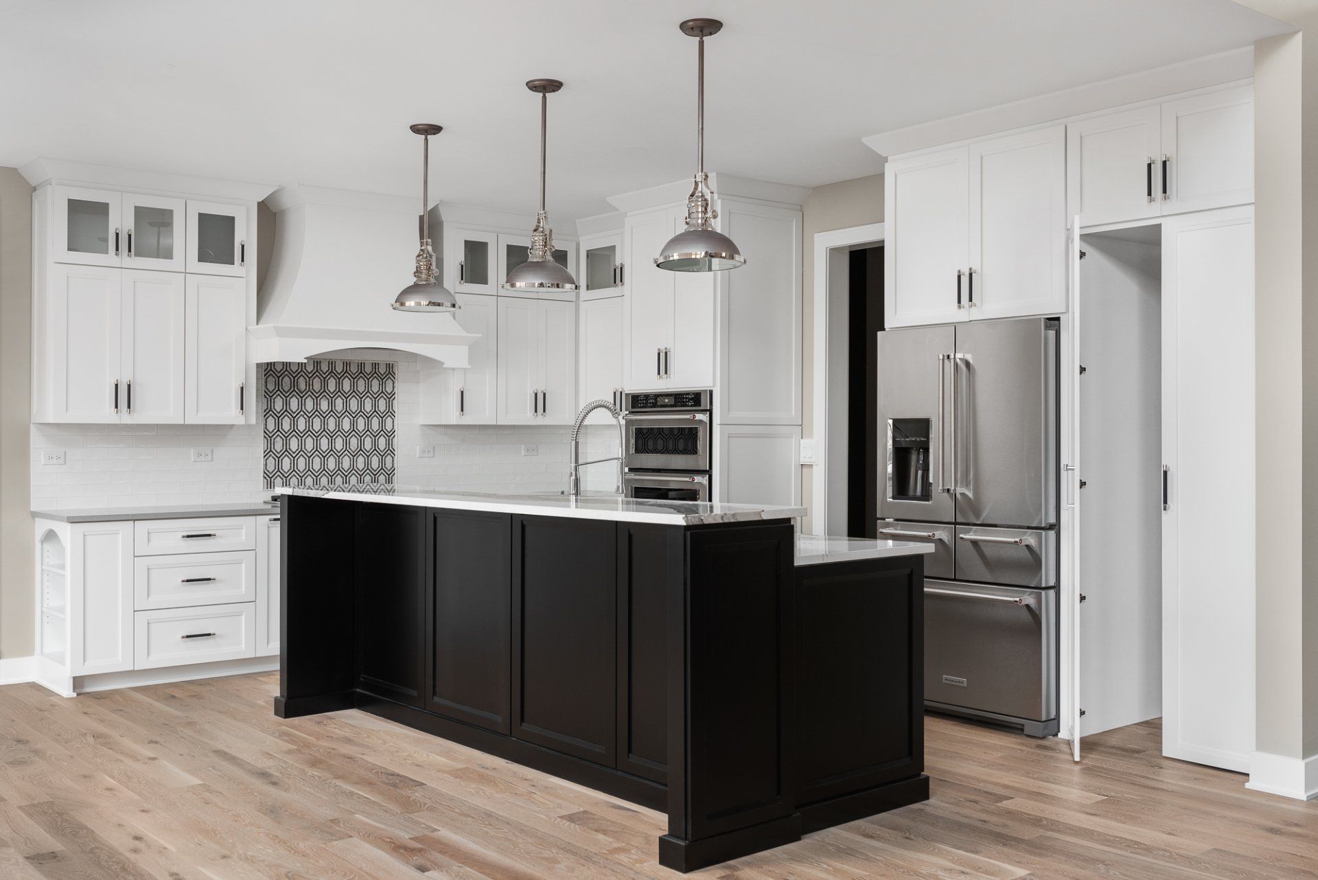 A kitchen with white cabinets and a black island.