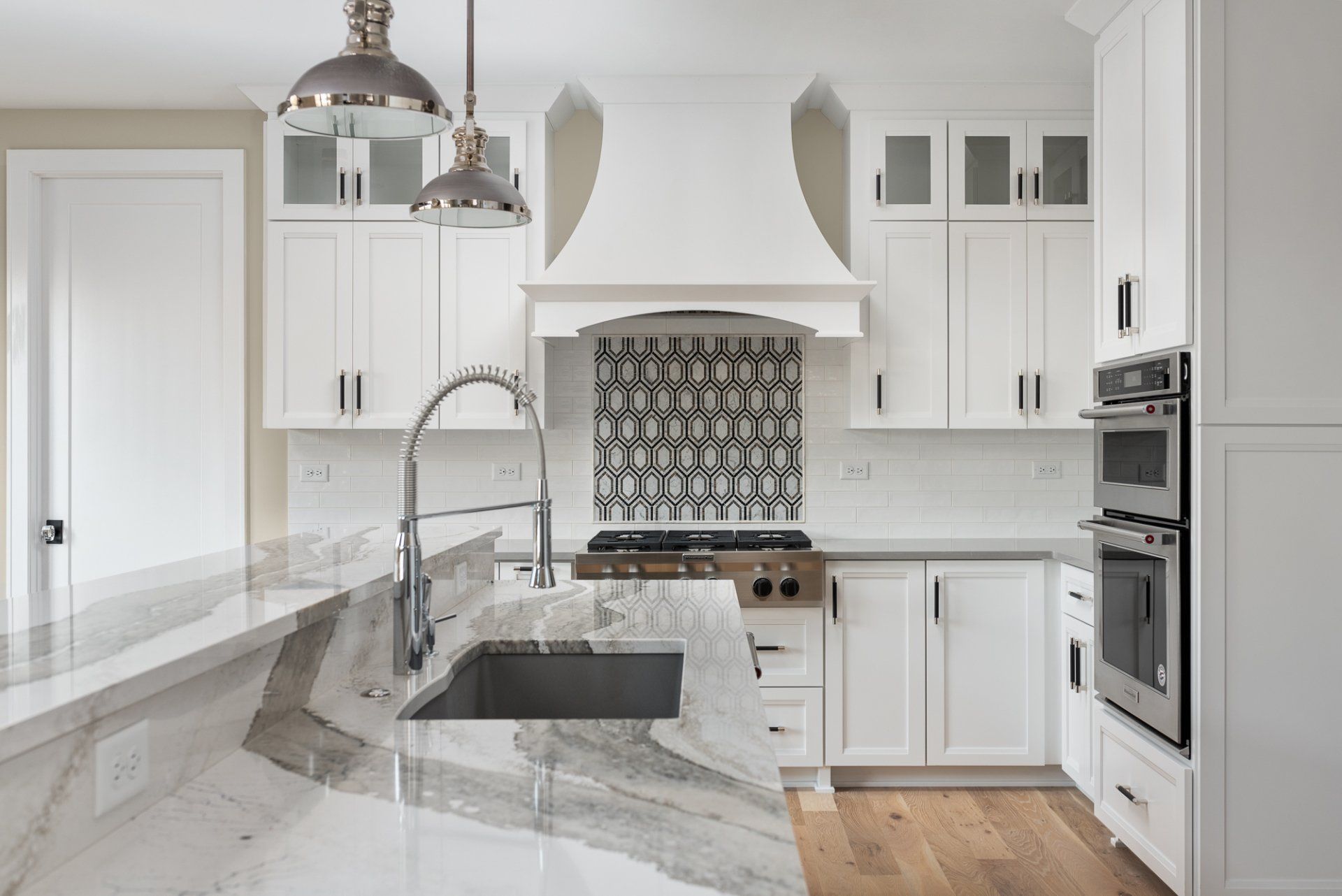 A kitchen with white cabinets , granite counter tops , stainless steel appliances and a sink.