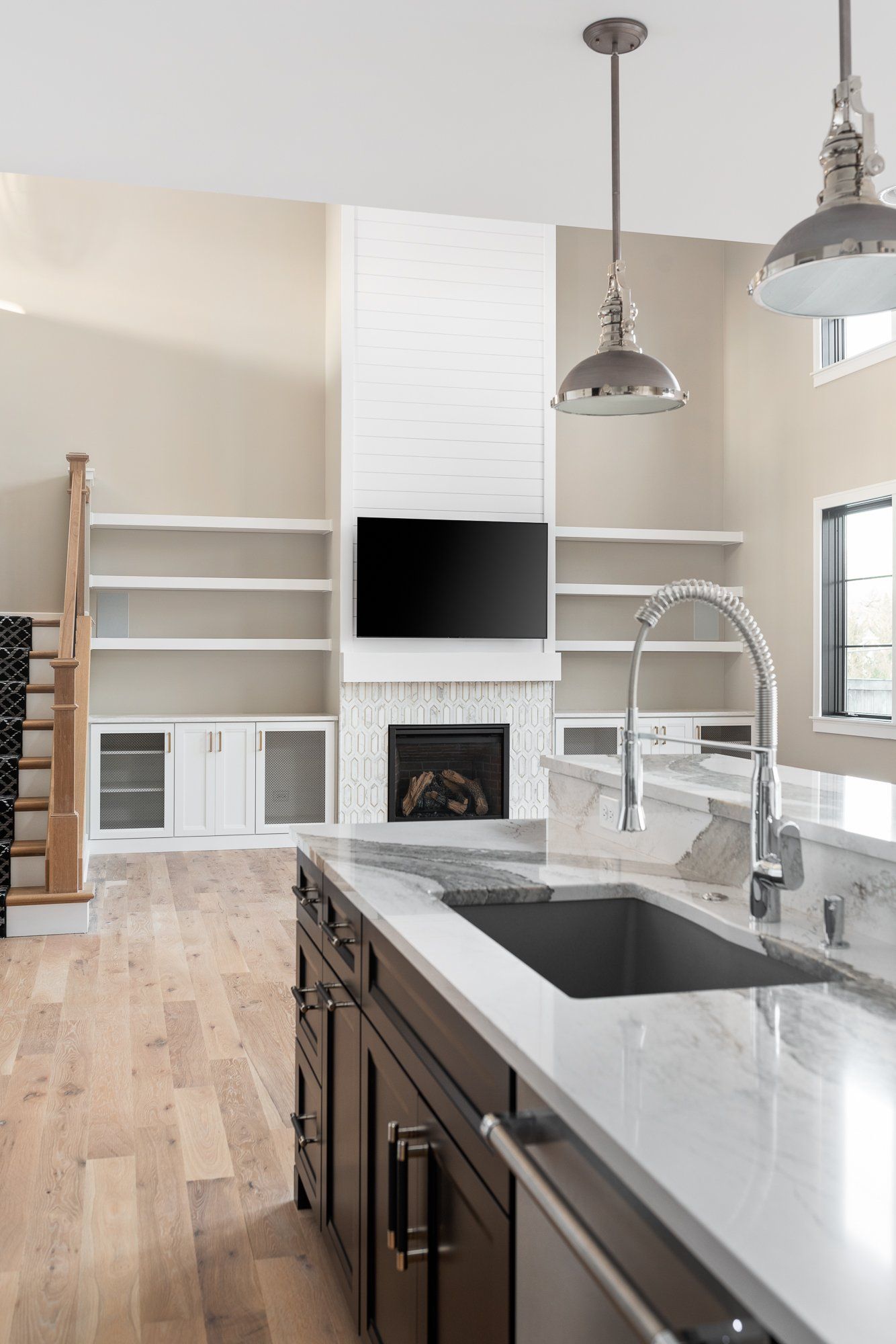 A kitchen with a sink , stove , television and fireplace.