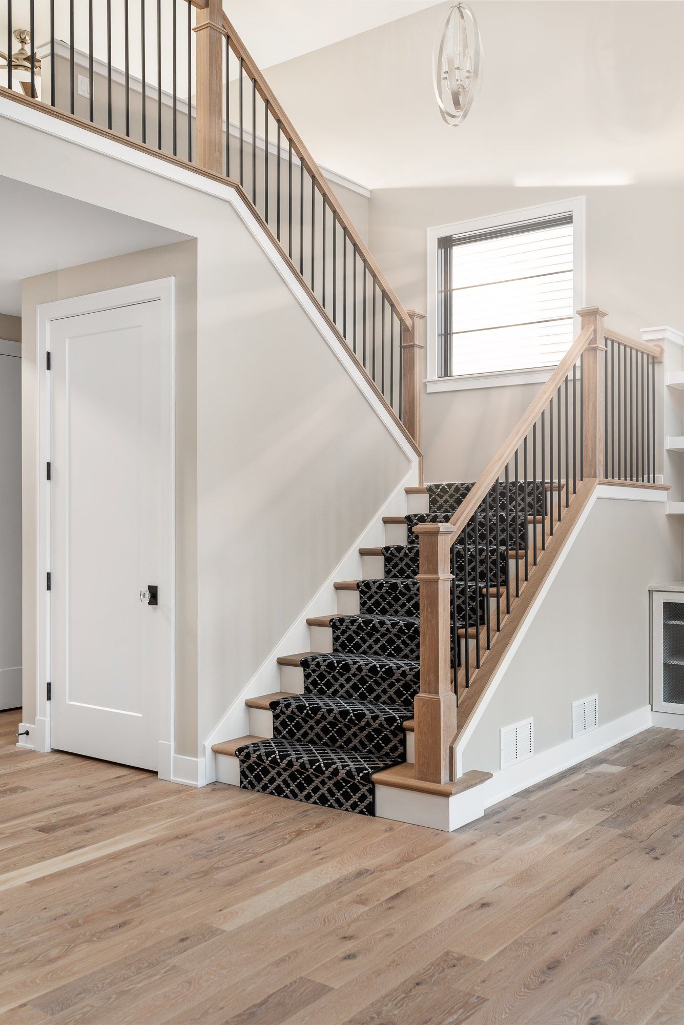 A staircase with a black carpet on the steps in a house.