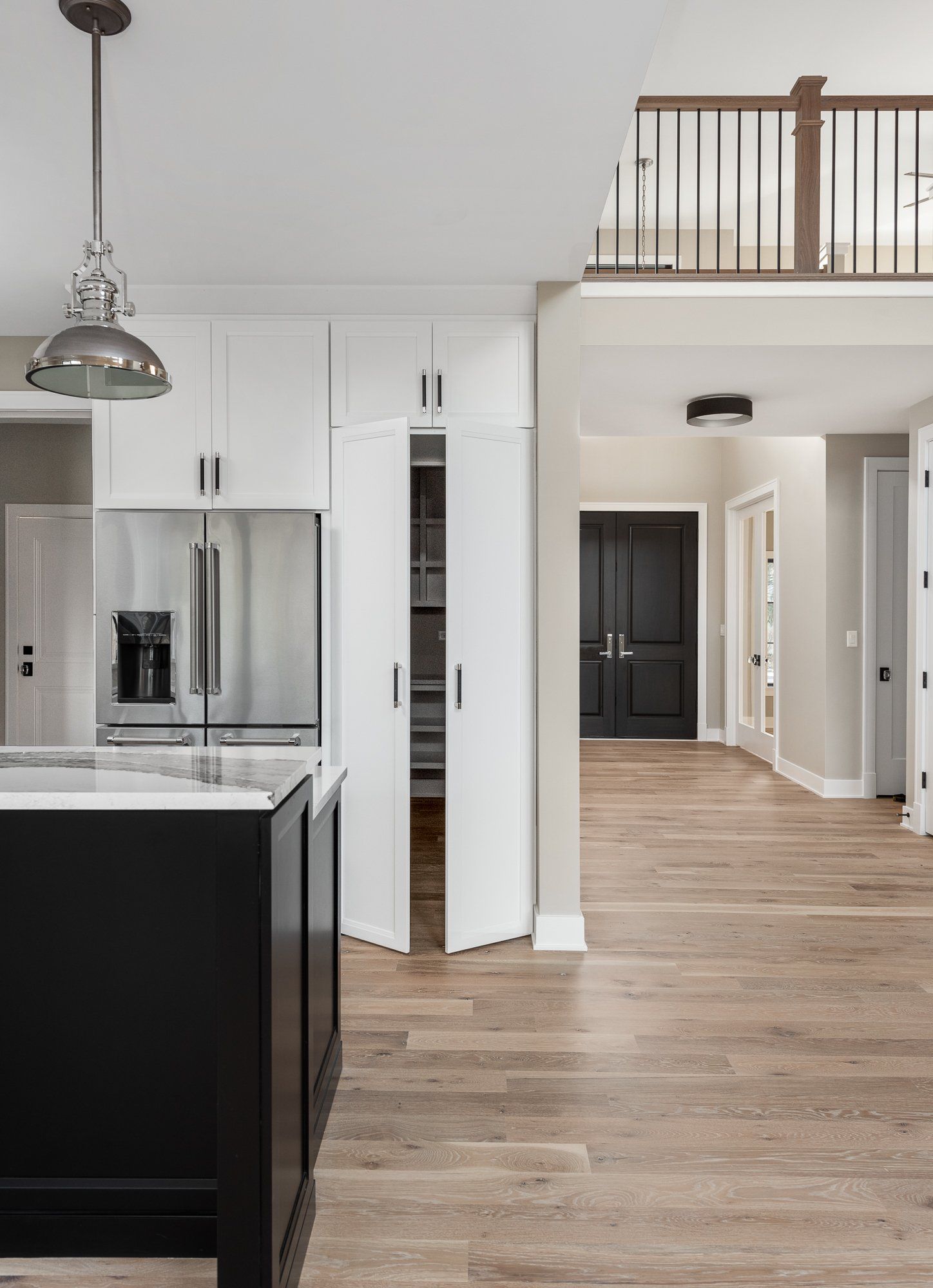 A kitchen with a black island and white cabinets