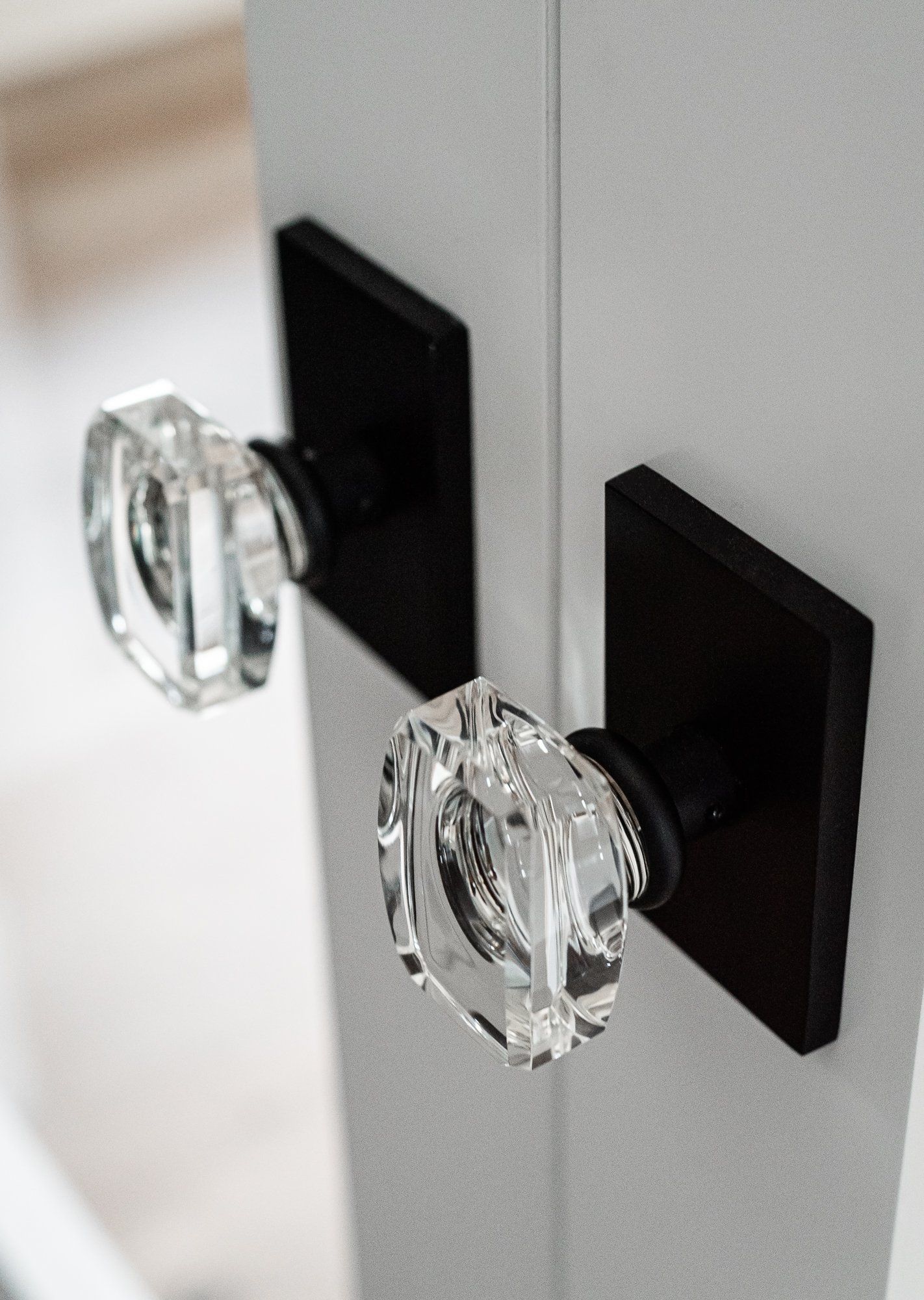 A pair of clear glass door knobs on a black door.