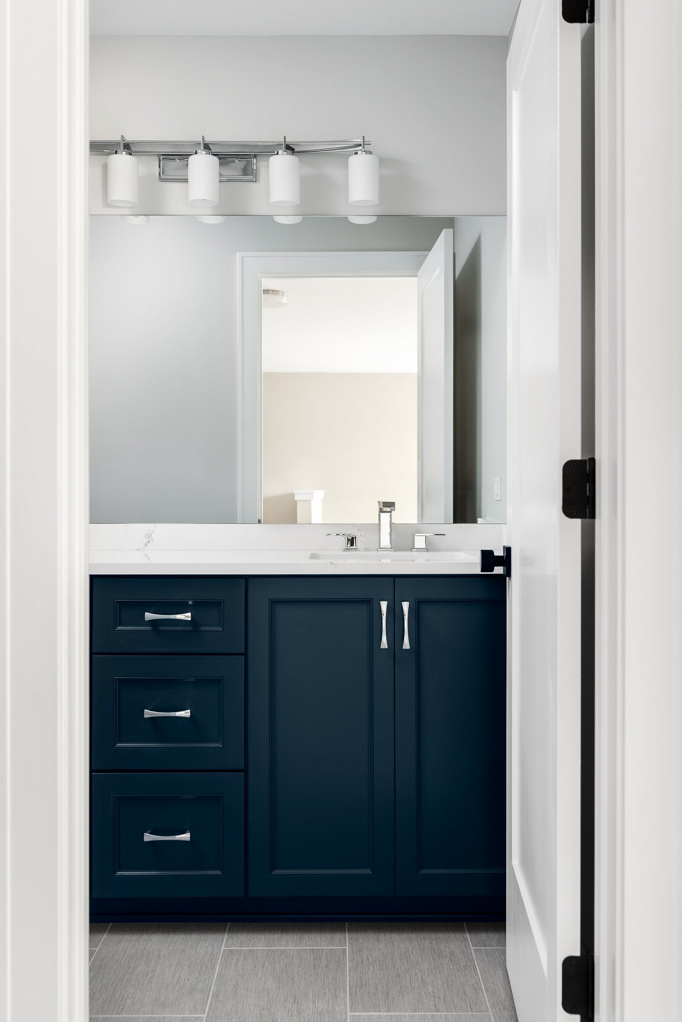 A bathroom with blue cabinets , a sink , and a mirror.