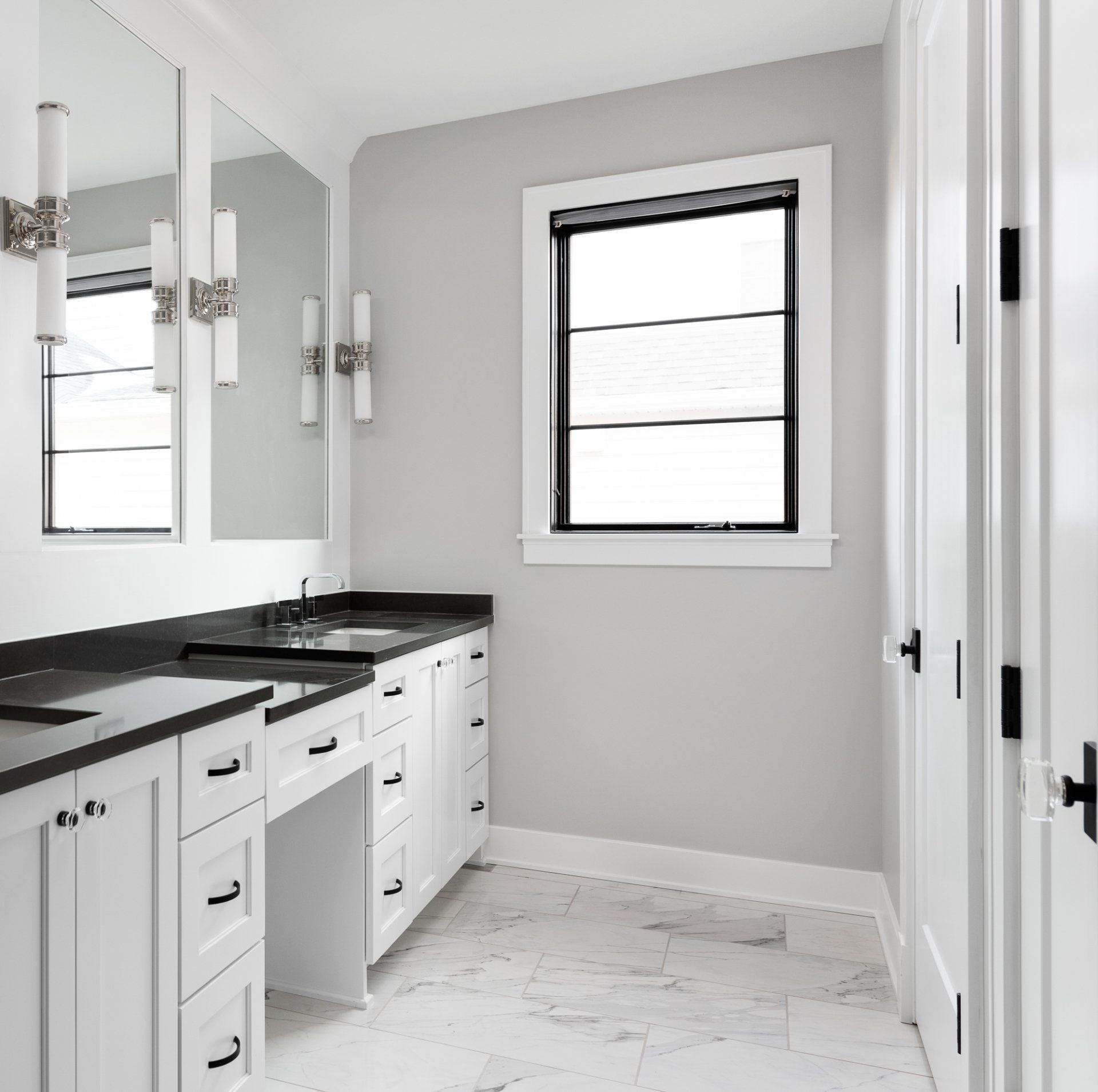 A bathroom with two sinks , two mirrors , and a window.