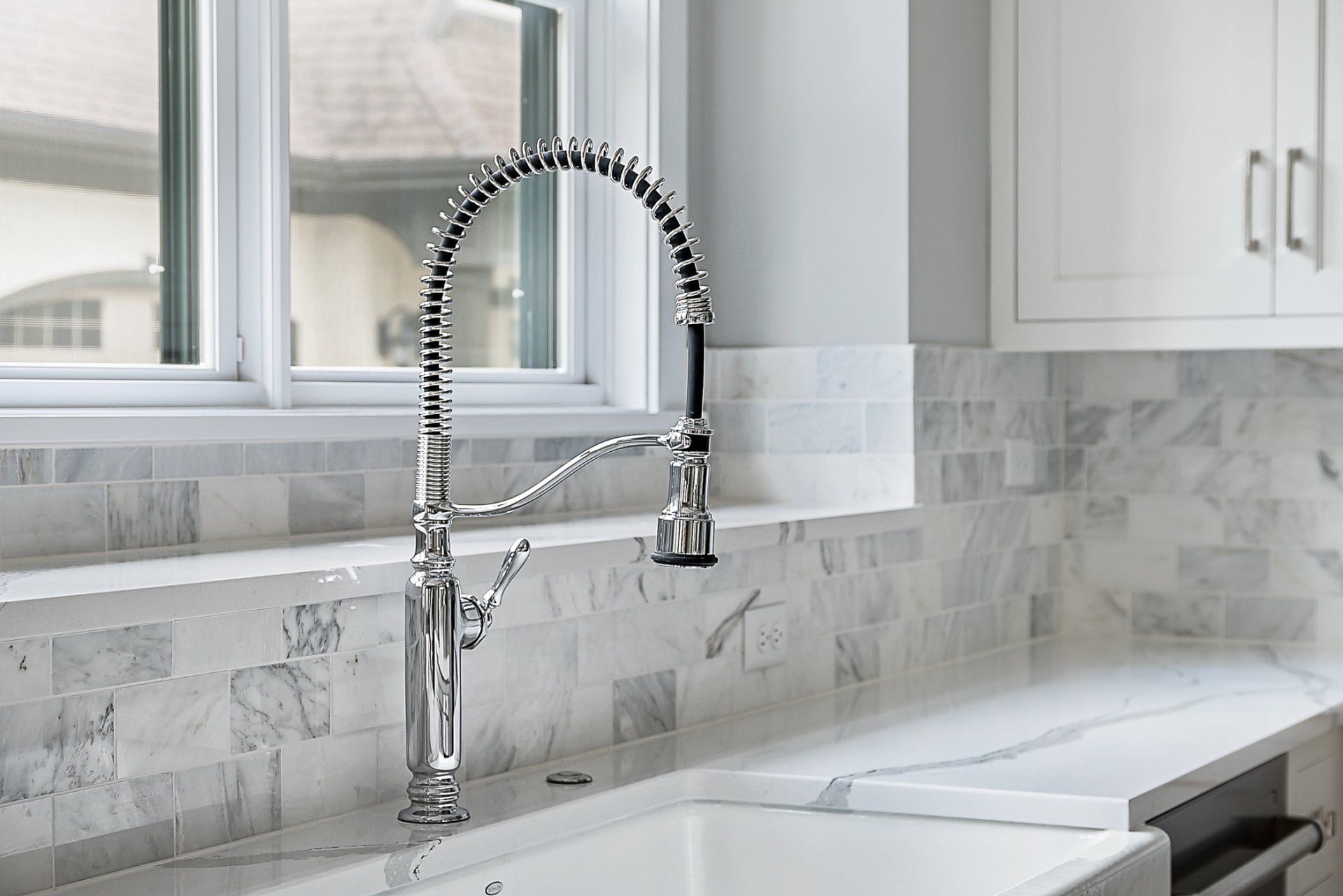 A kitchen sink with a faucet and a window in the background.