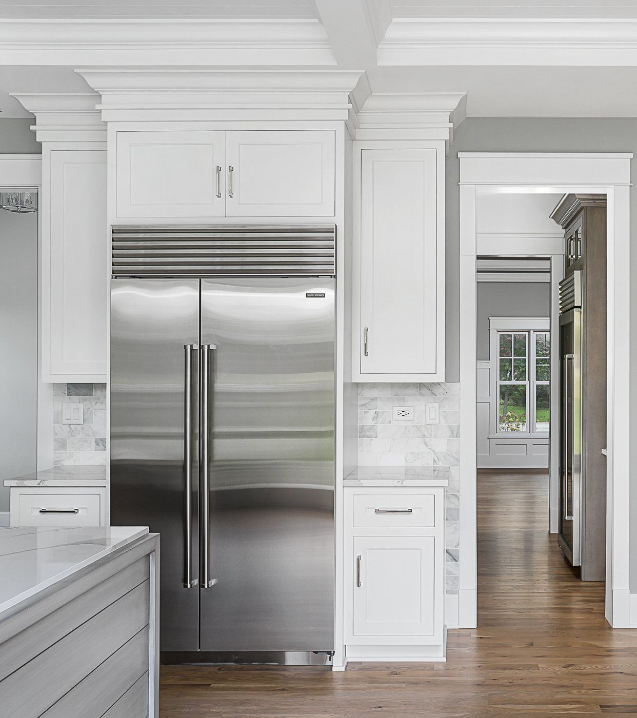 A kitchen with white cabinets and a stainless steel refrigerator.