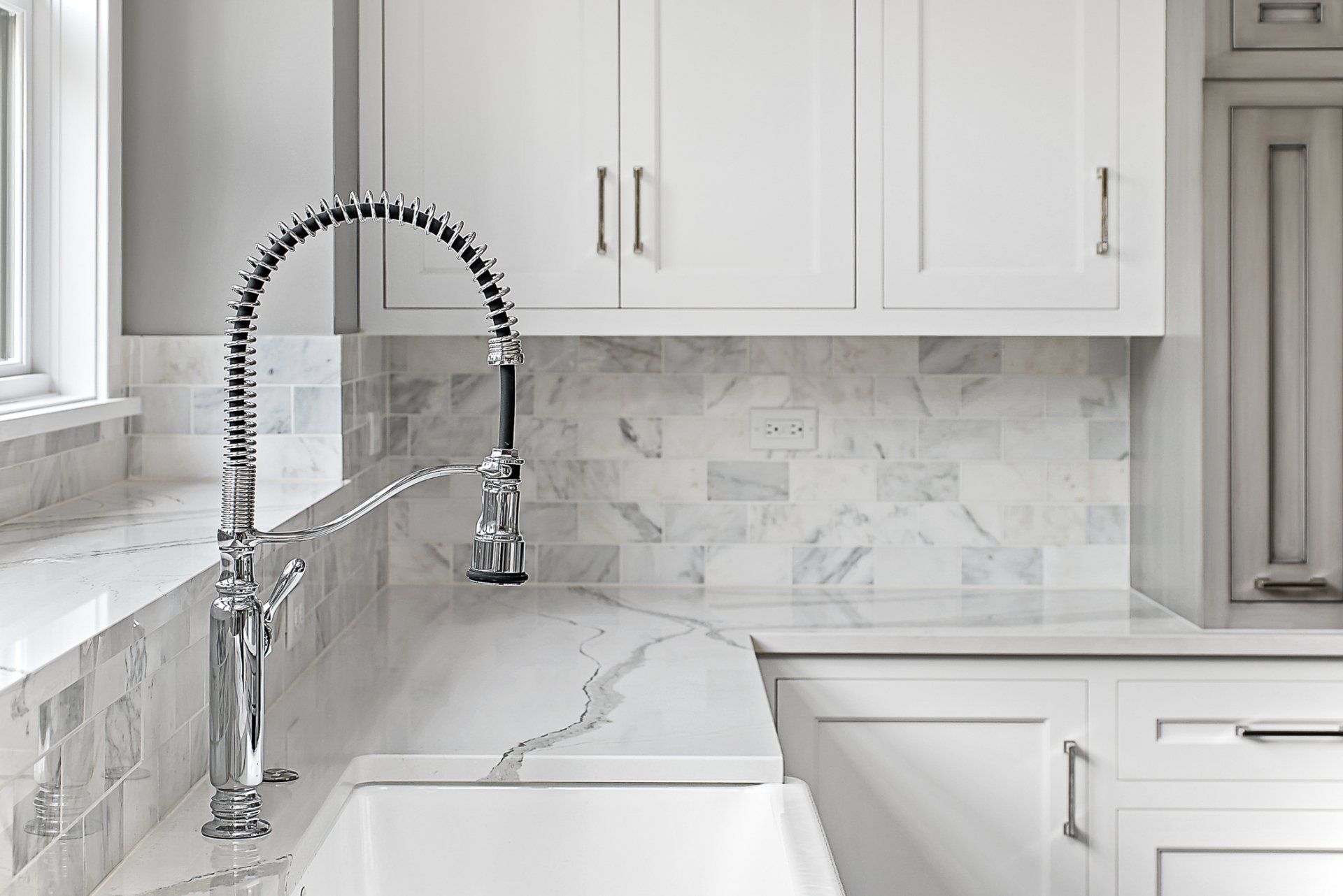 A kitchen sink with a faucet and white cabinets.