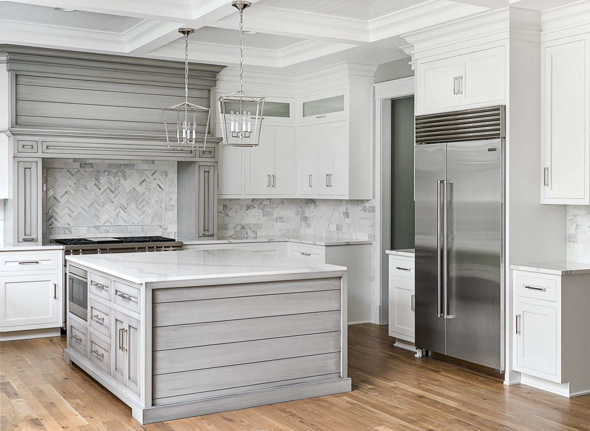 A kitchen with white cabinets , stainless steel appliances , and a large island.