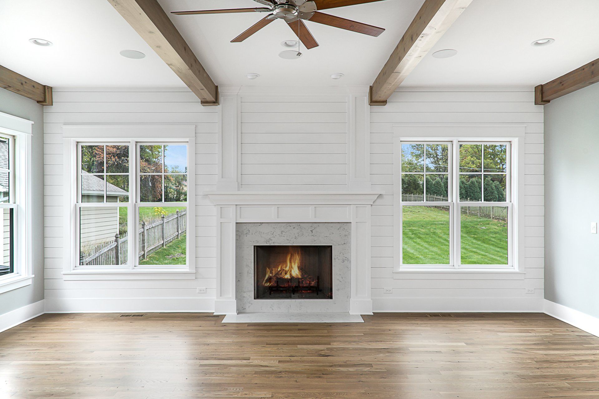 An empty living room with a fireplace and a ceiling fan.