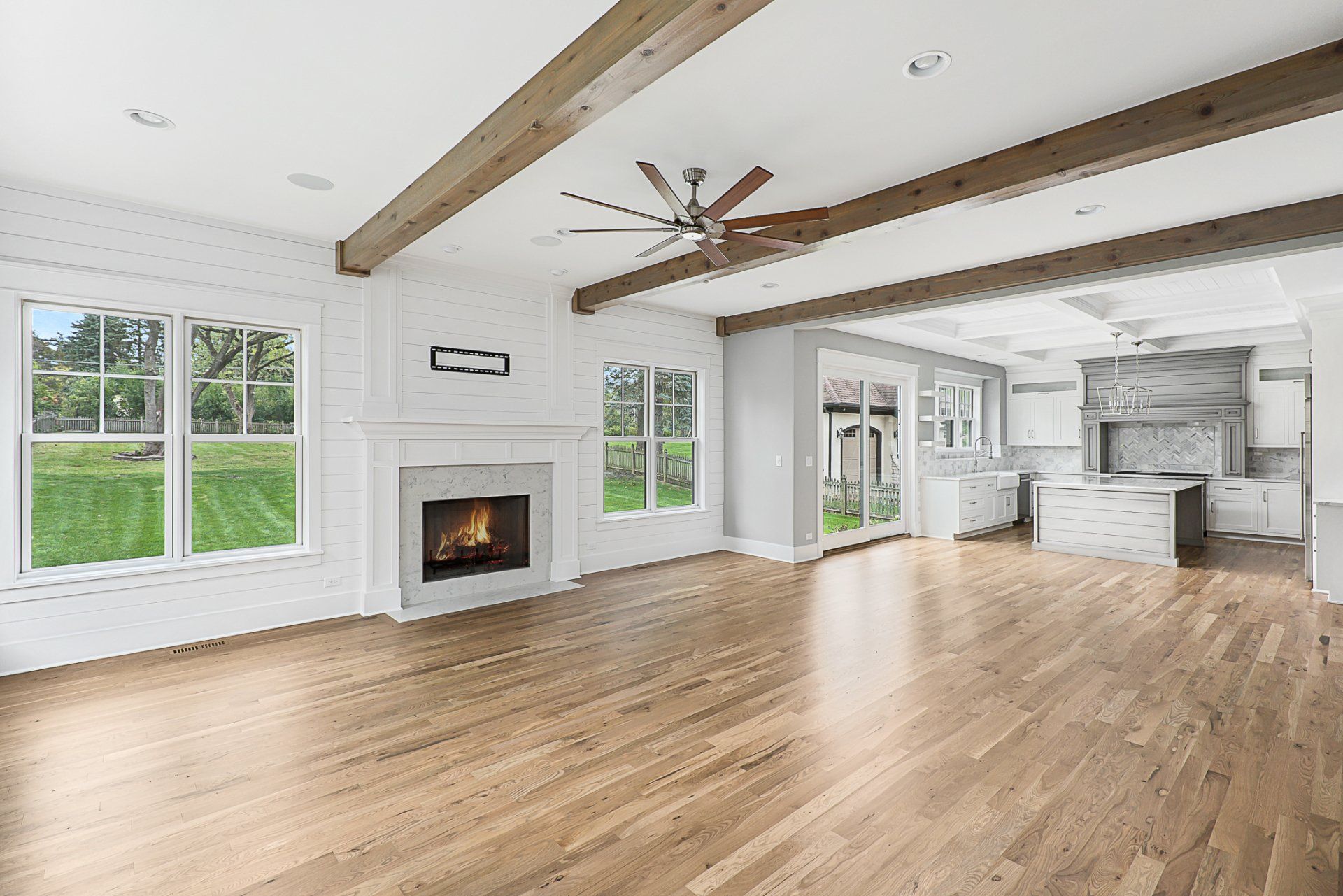 An empty living room with hardwood floors , a fireplace and a ceiling fan.