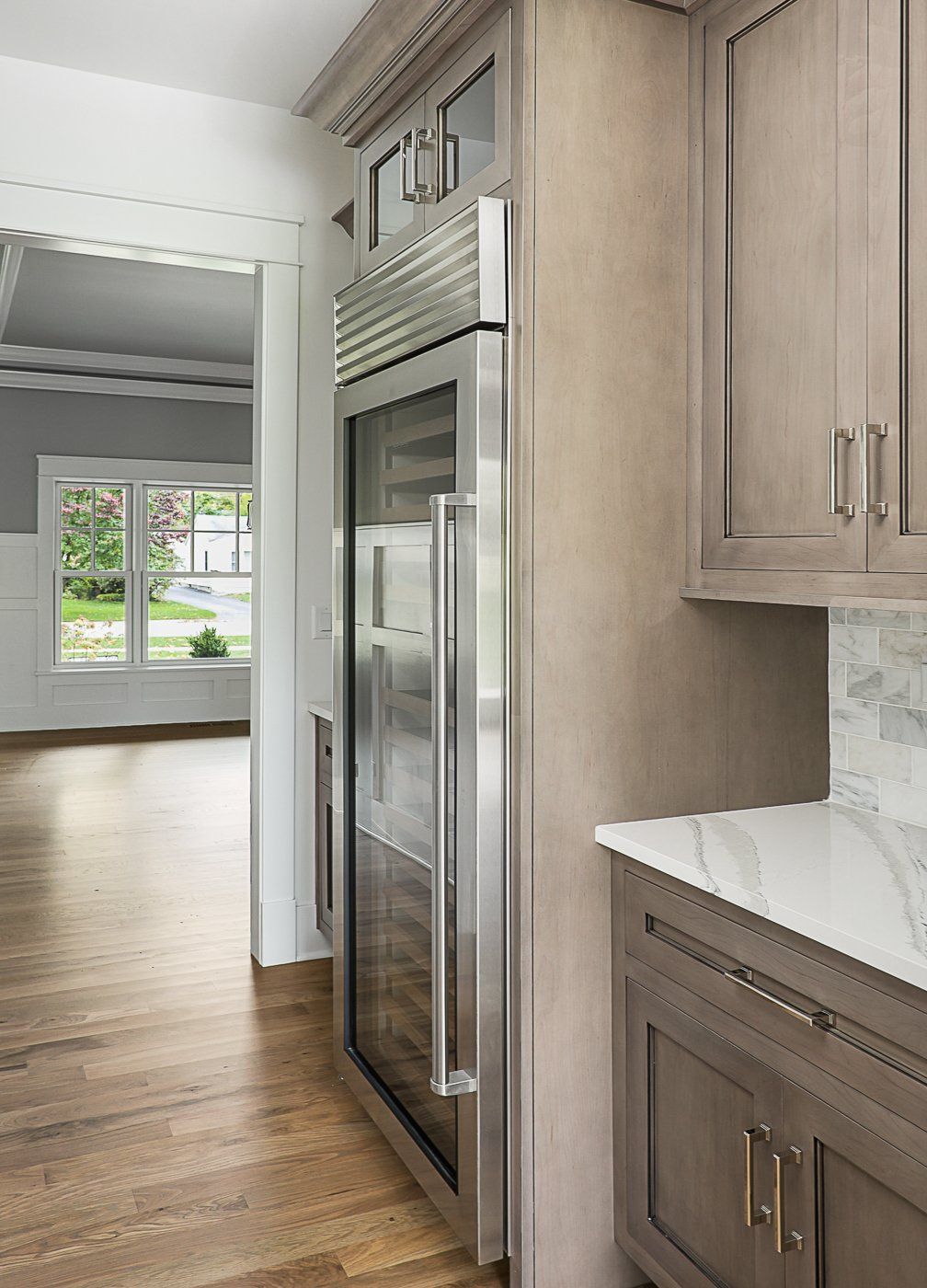A kitchen with wooden cabinets and a stainless steel refrigerator with a glass door.