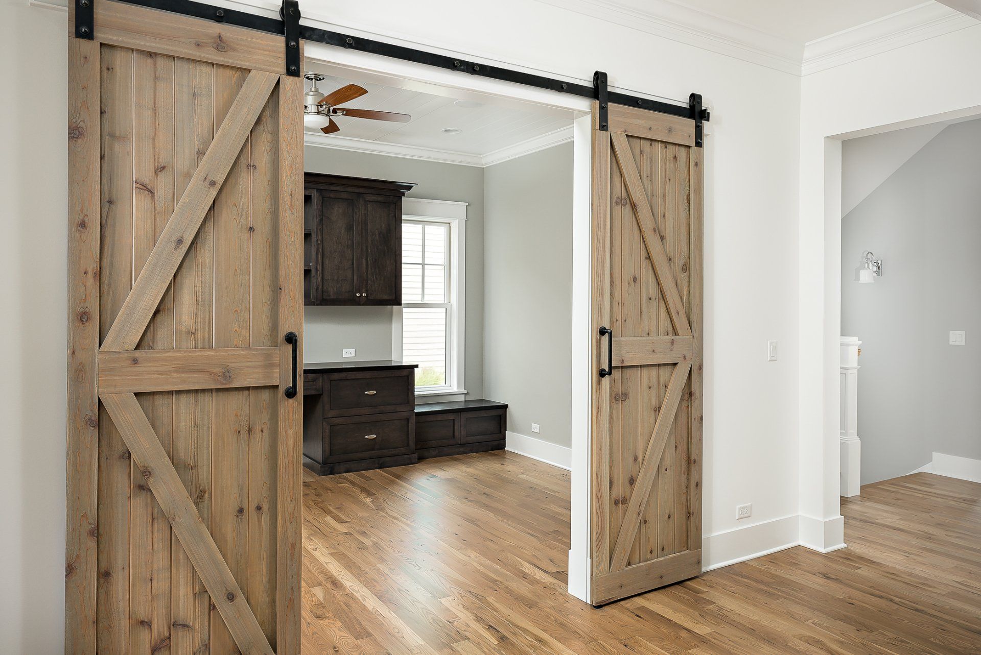 A bedroom with sliding barn doors and hardwood floors.