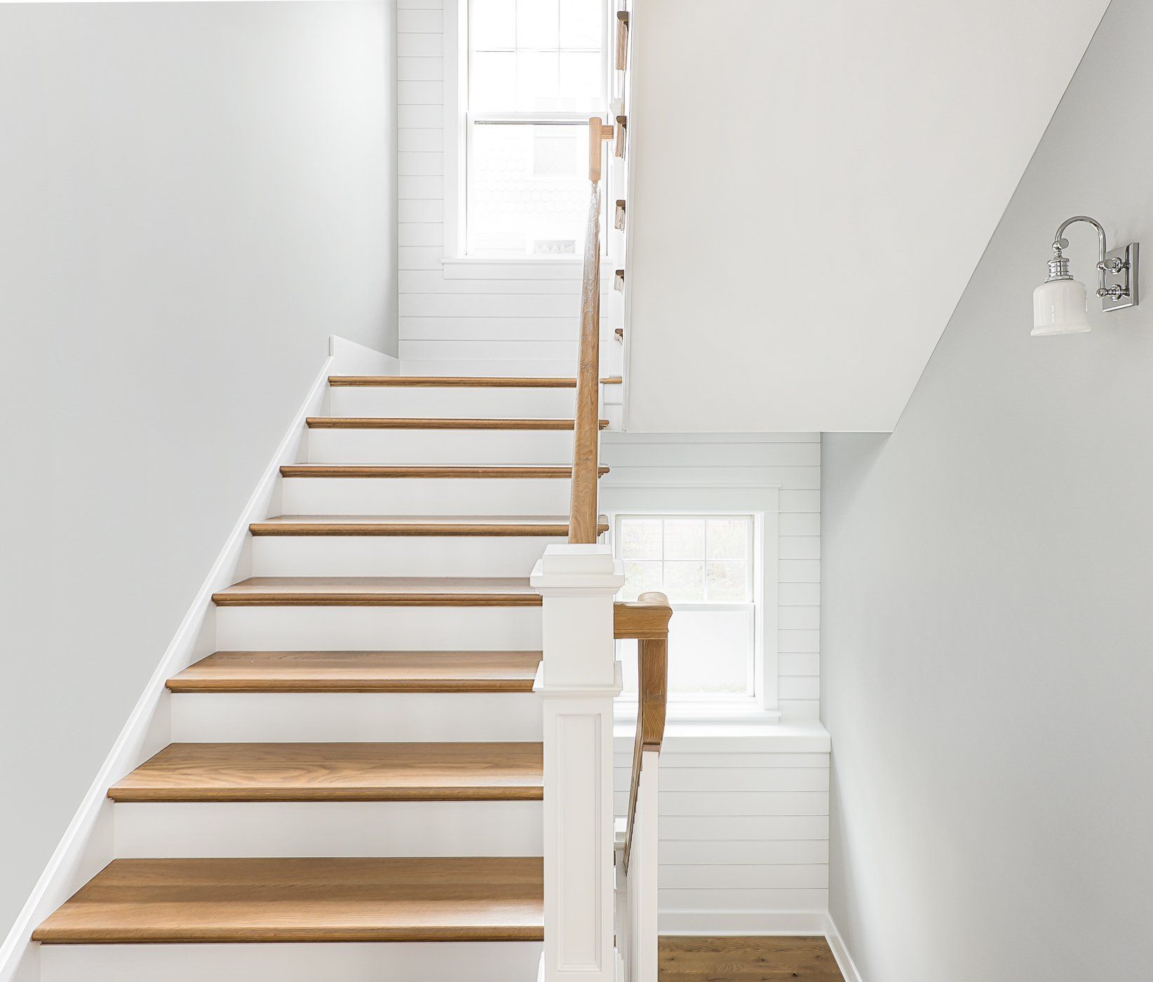 A white staircase with wooden steps and a window.