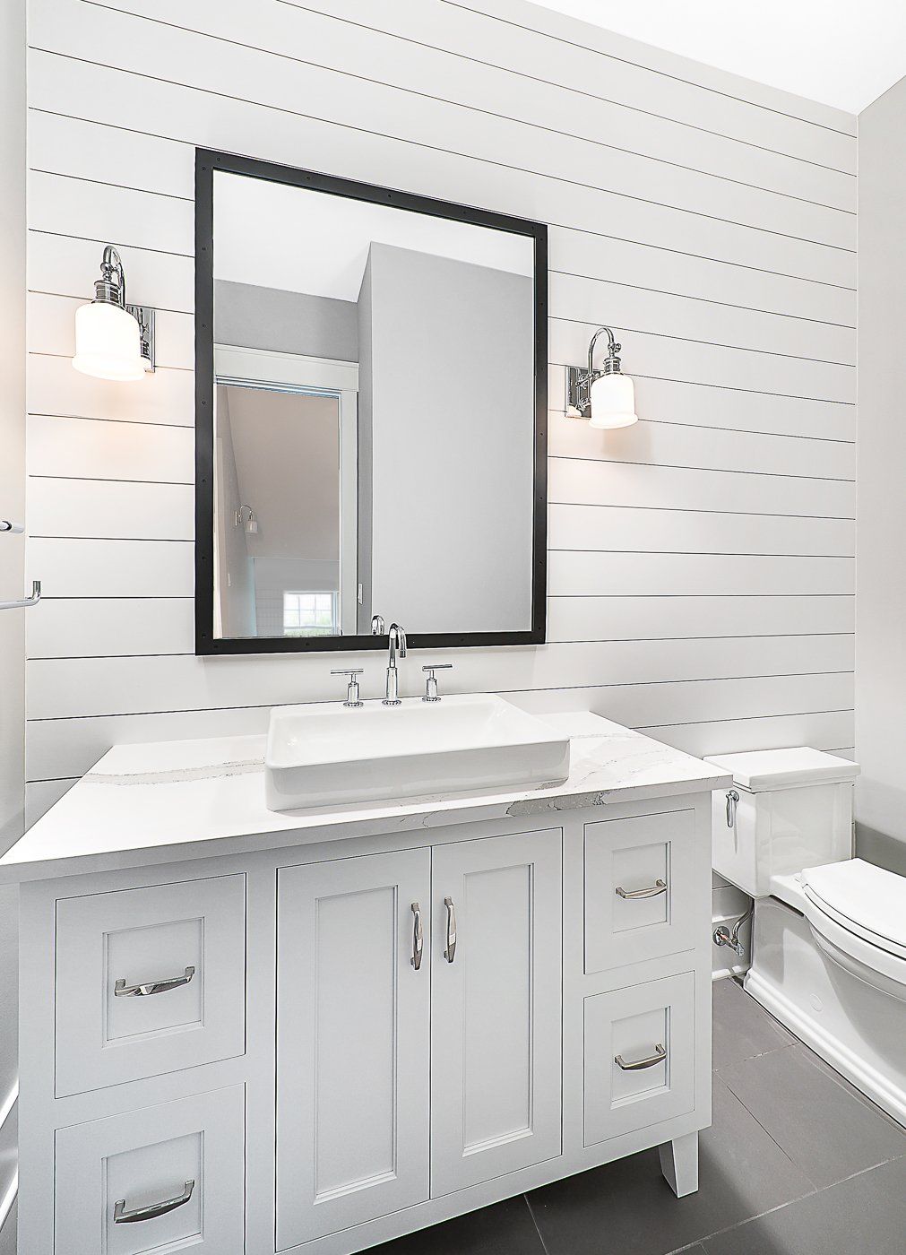 A bathroom with a sink , toilet and mirror.