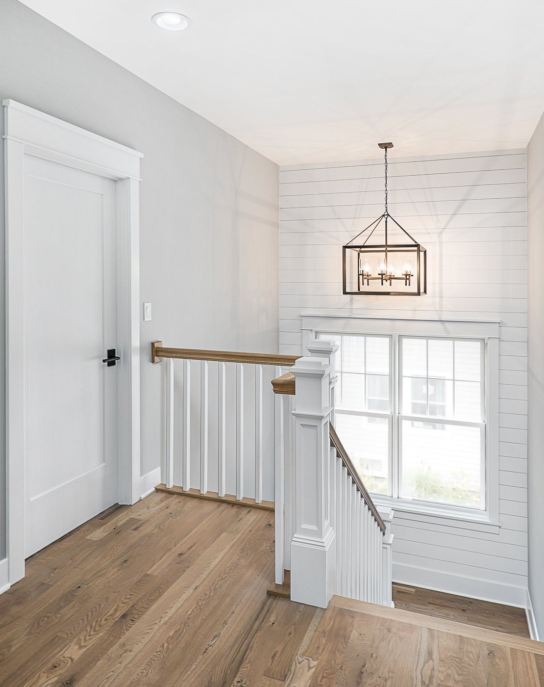 There is a staircase with a wooden railing and a window.