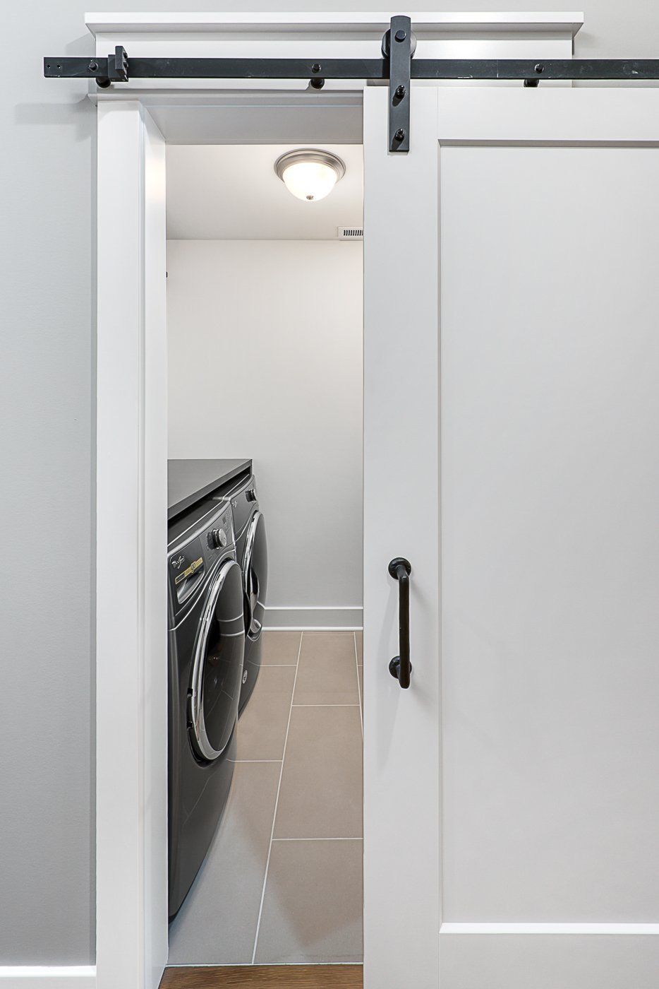 A laundry room with a sliding barn door leading to a washer and dryer.