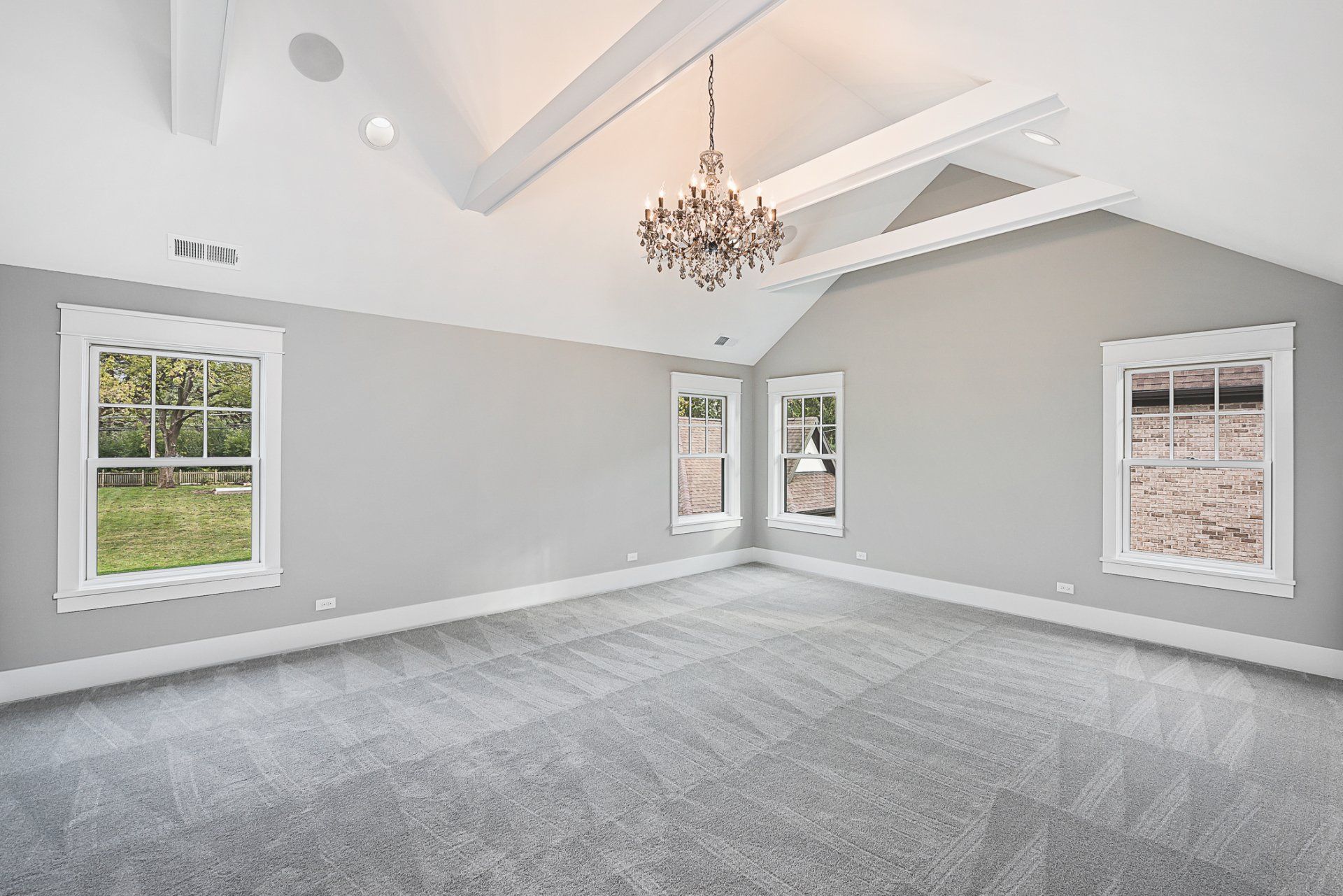 A large empty room with a vaulted ceiling and a chandelier.