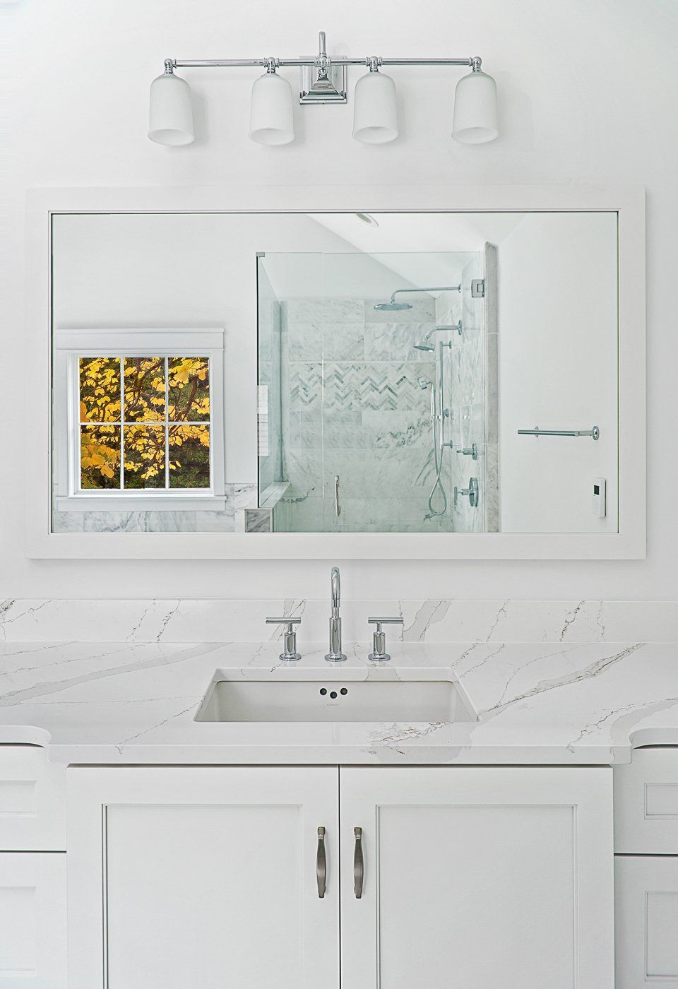 A bathroom with a sink , mirror , and window.
