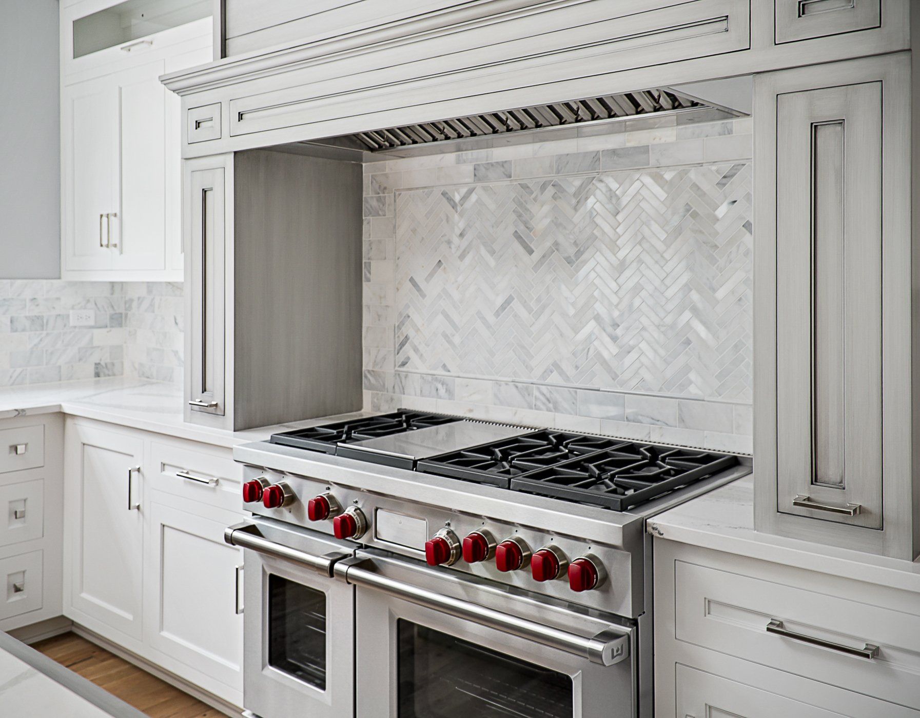A kitchen with a stove top oven and white cabinets.