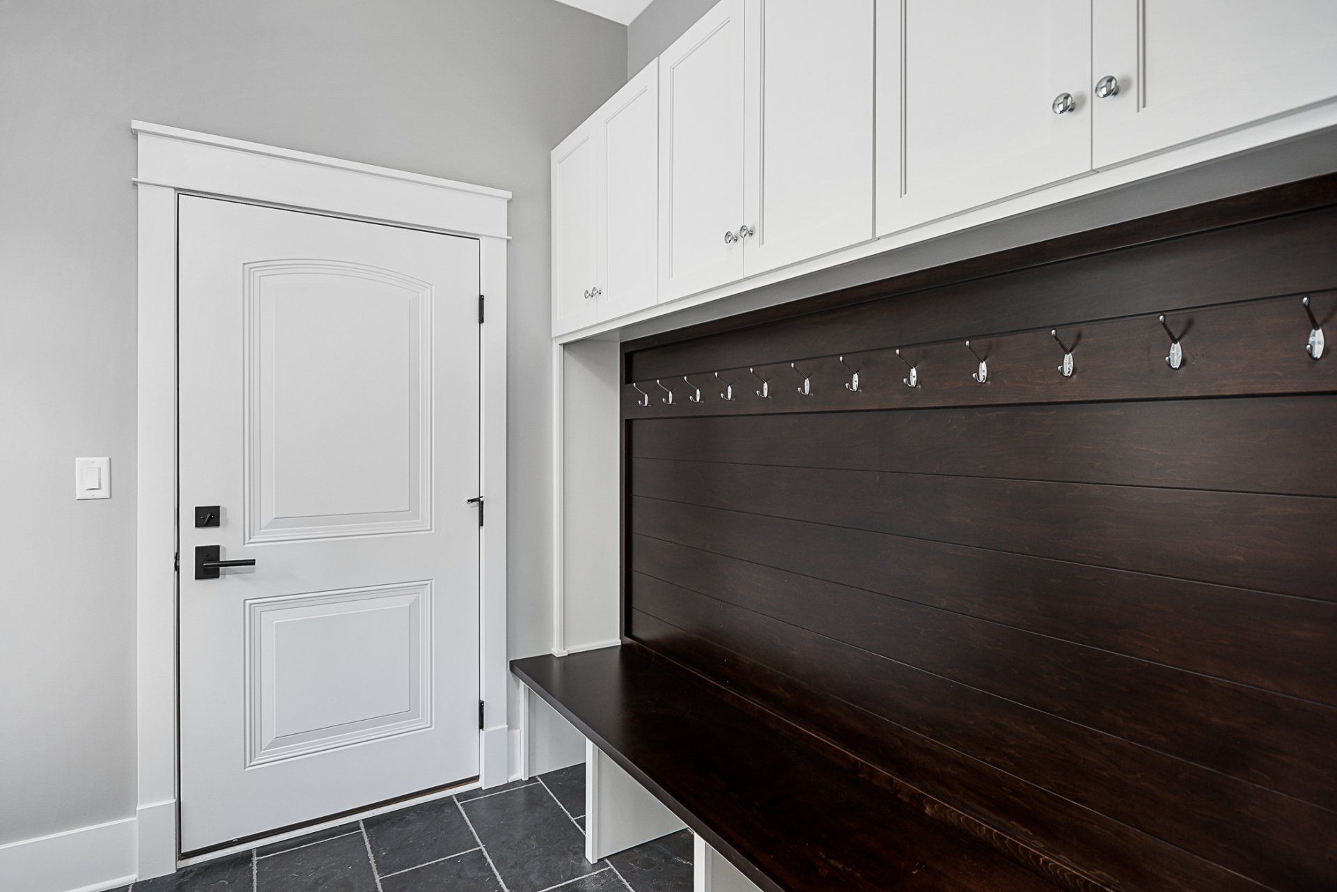 A mud room with white cabinets and a wooden bench.