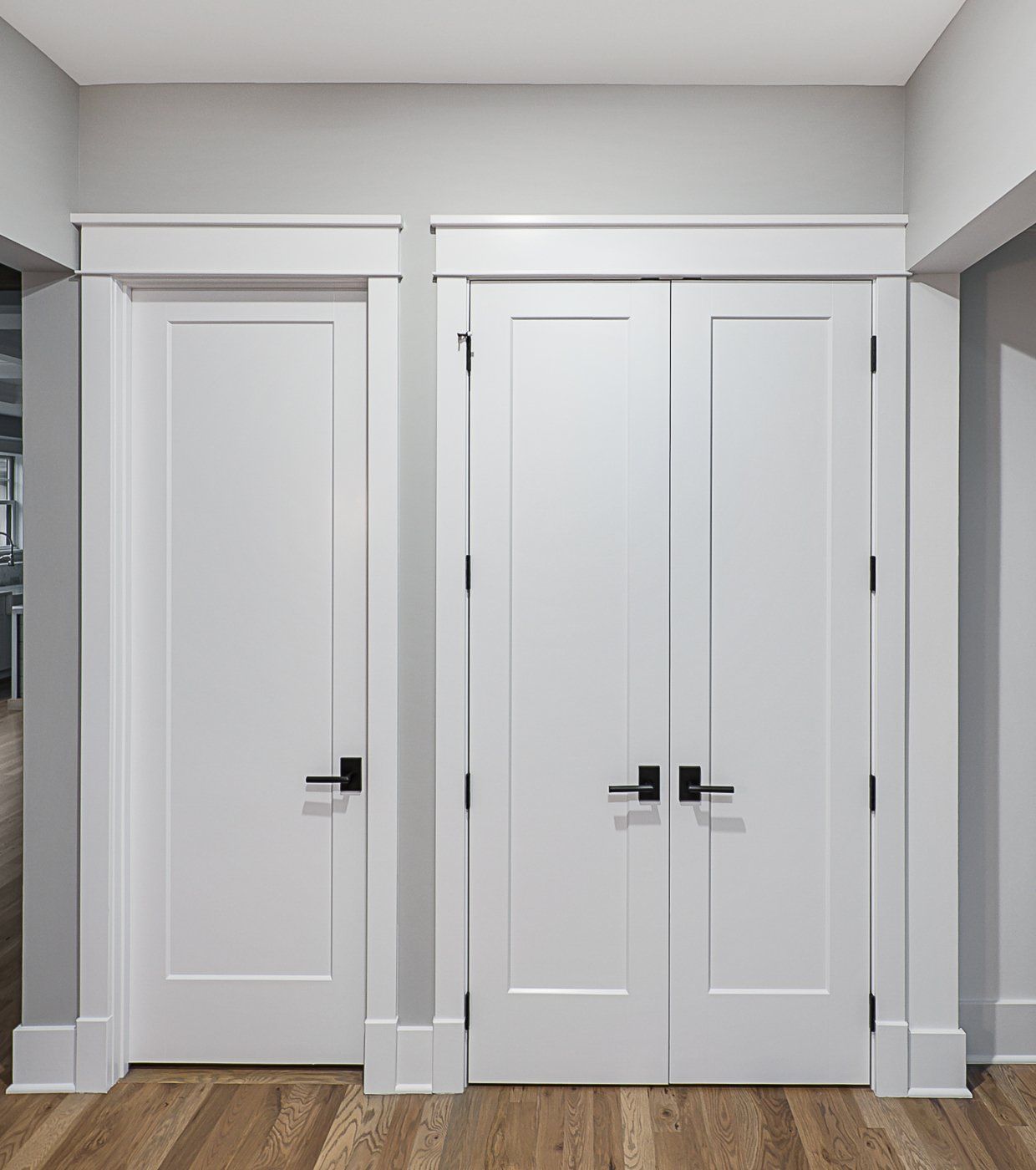 A hallway with two white doors and a wooden floor.