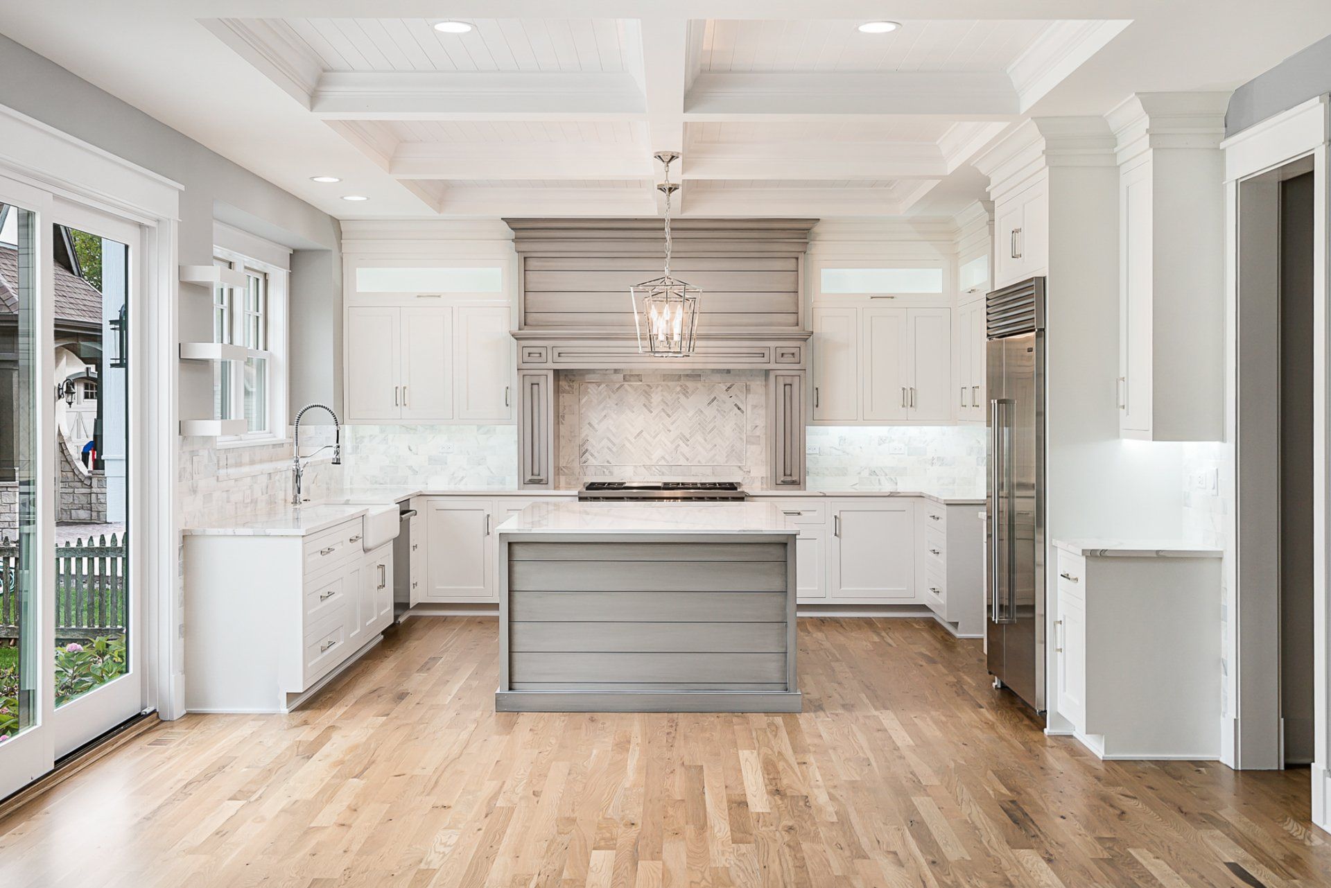 A kitchen with white cabinets , hardwood floors , stainless steel appliances and a large island.