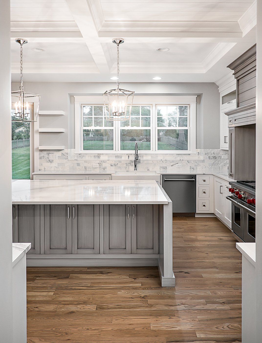 A kitchen with gray cabinets , white counter tops , and a large island.
