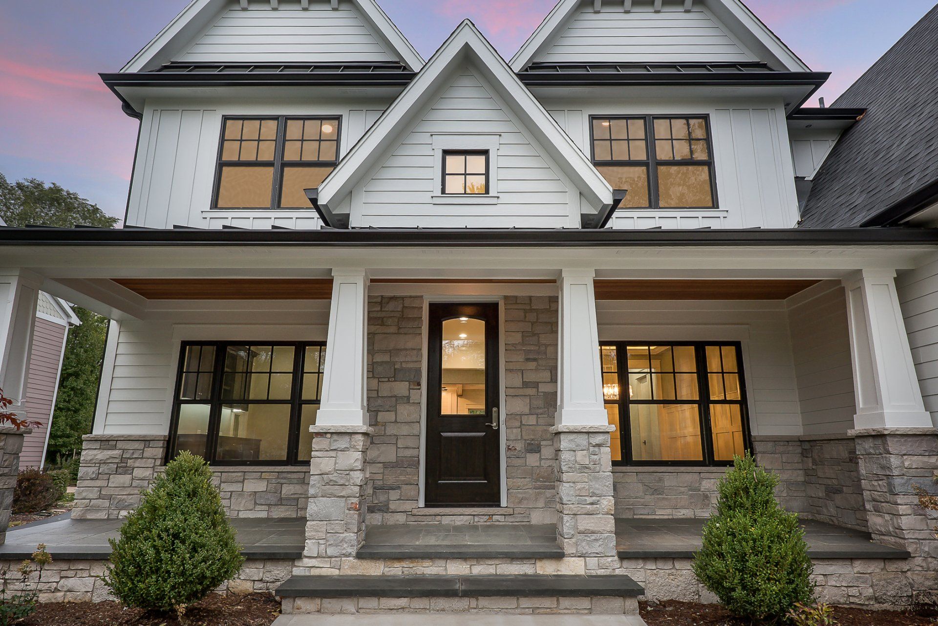 The front of a white house with a black door and a porch.