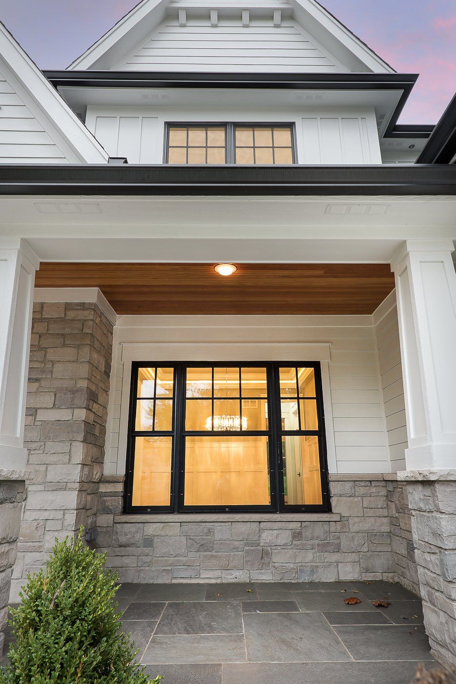 The front of a house with a porch and a large window.
