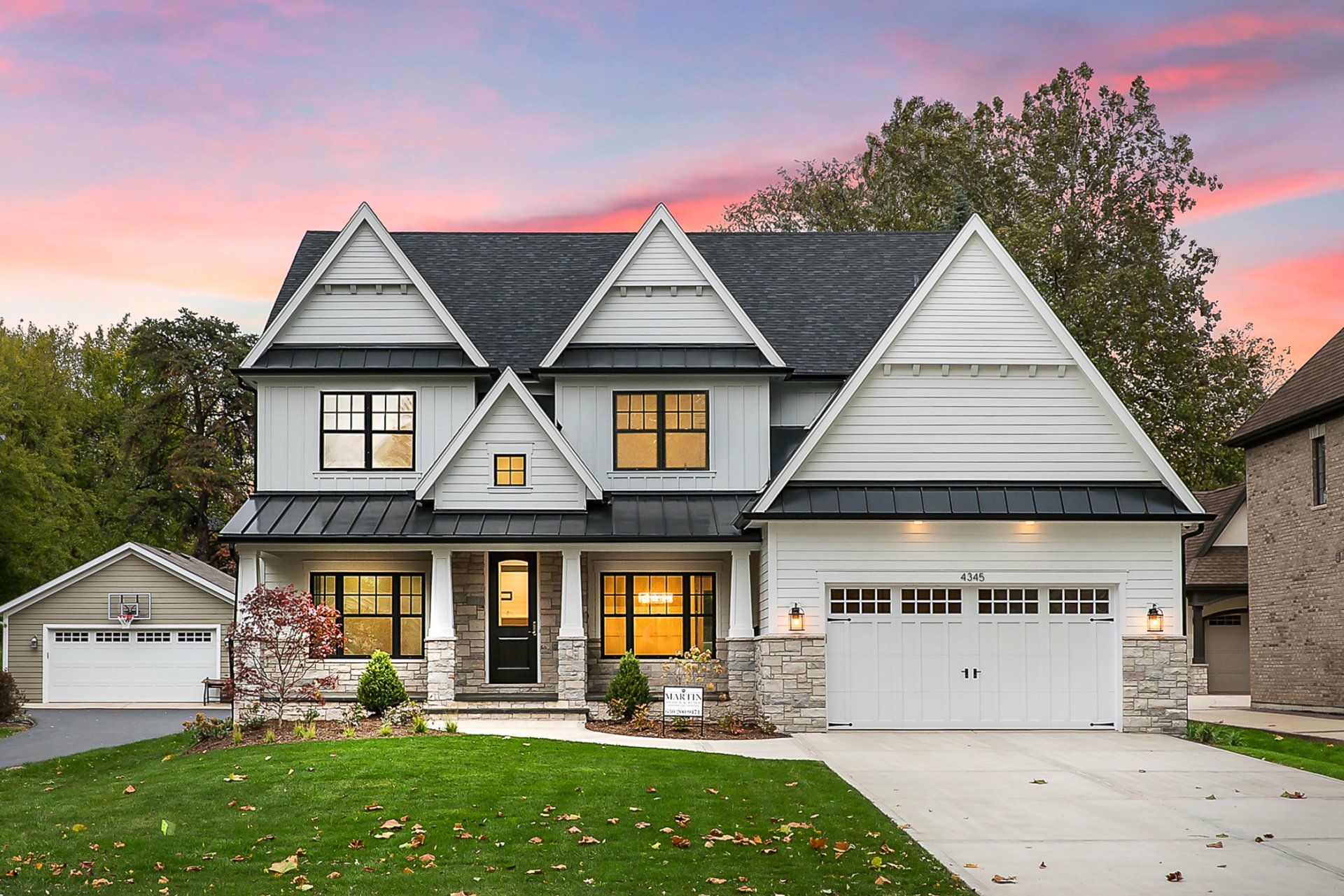 A large white house with a black roof is for sale.