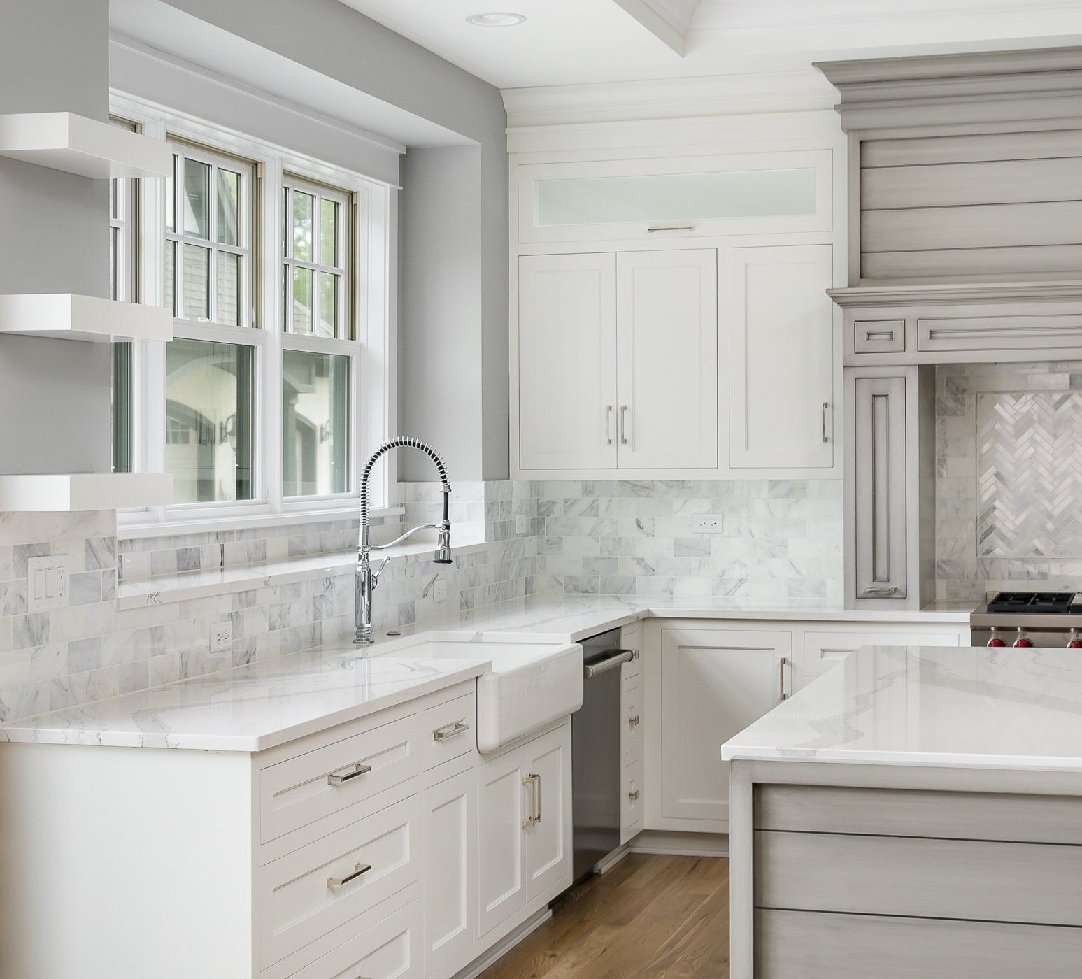 A kitchen with white cabinets and marble counter tops