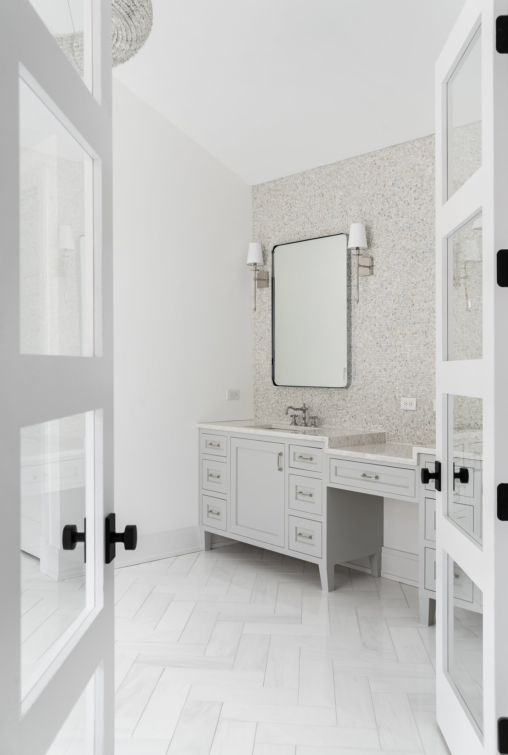 A bathroom with white cabinets , a sink and a mirror.