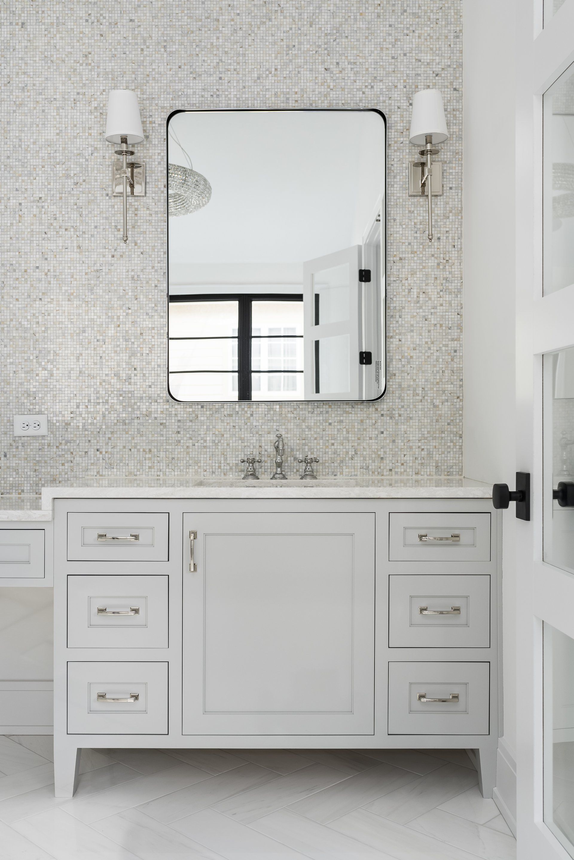 A bathroom with a sink , mirror and drawers.
