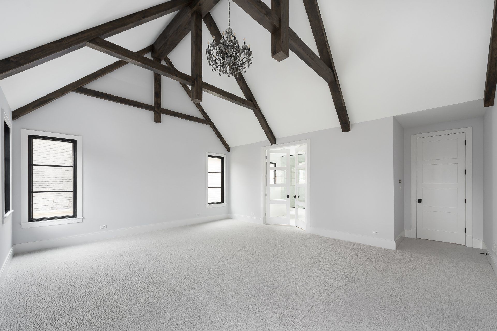An empty room with a vaulted ceiling and wooden beams